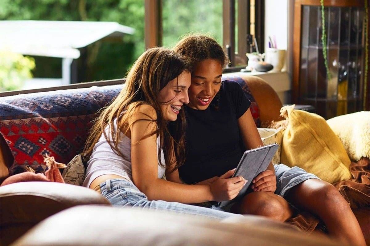 Two teenagers sitting together looking at tablet