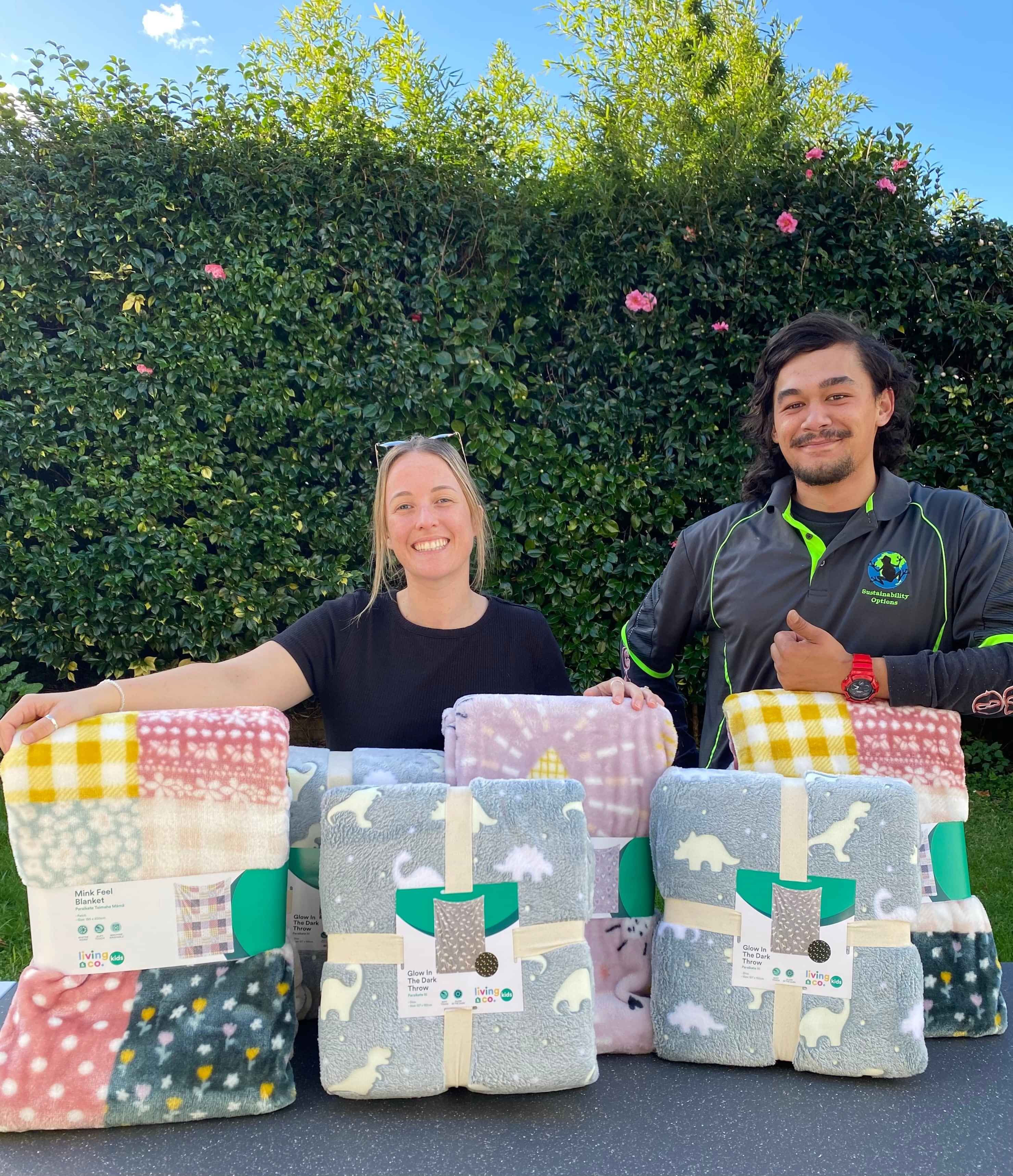 Man and woman standing in front of pile of blankets