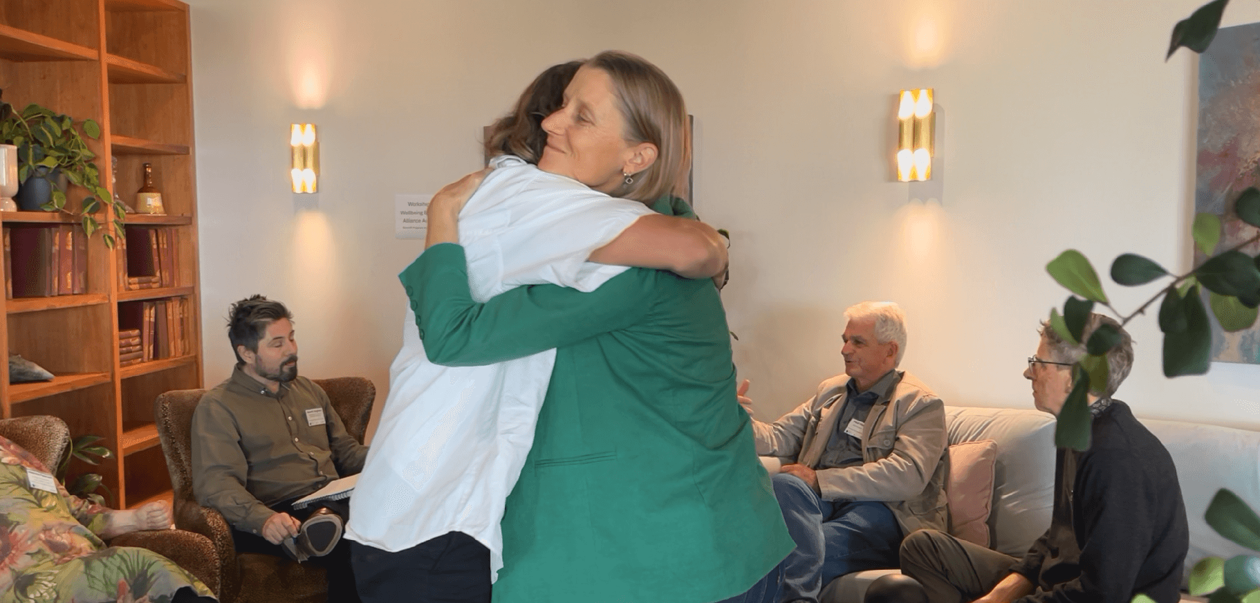 Two people embracing in a warm greeting during a community or networking event