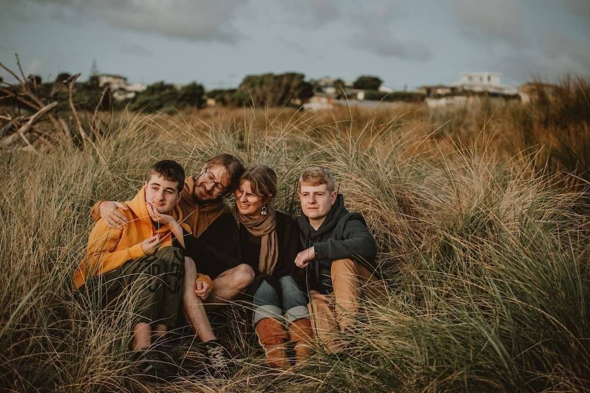 Mel Curwood, Payment Protection Coach, with her family in the dunes as the sun sets in the Waikato, NZ.