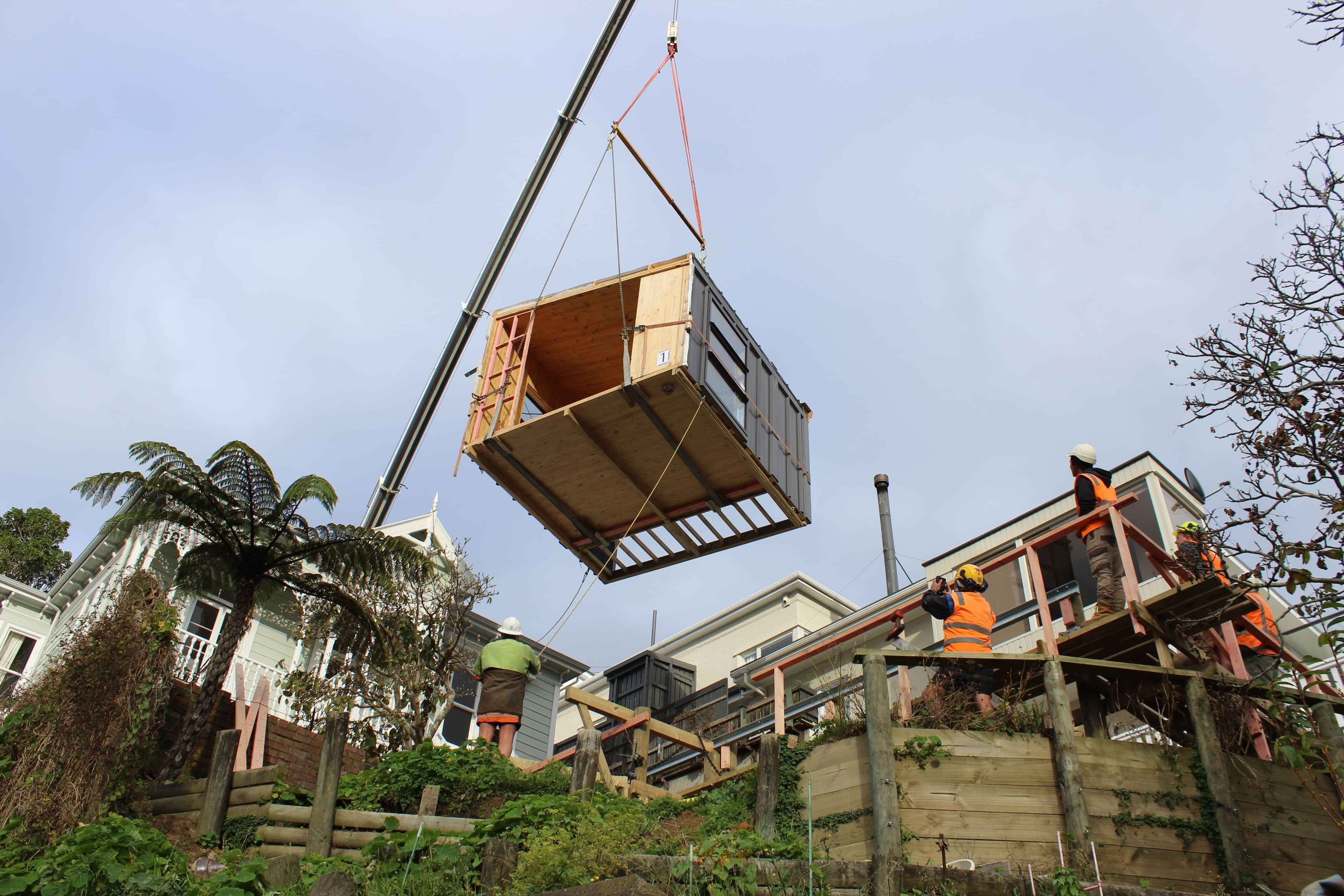Module of house being craned onto a hillside