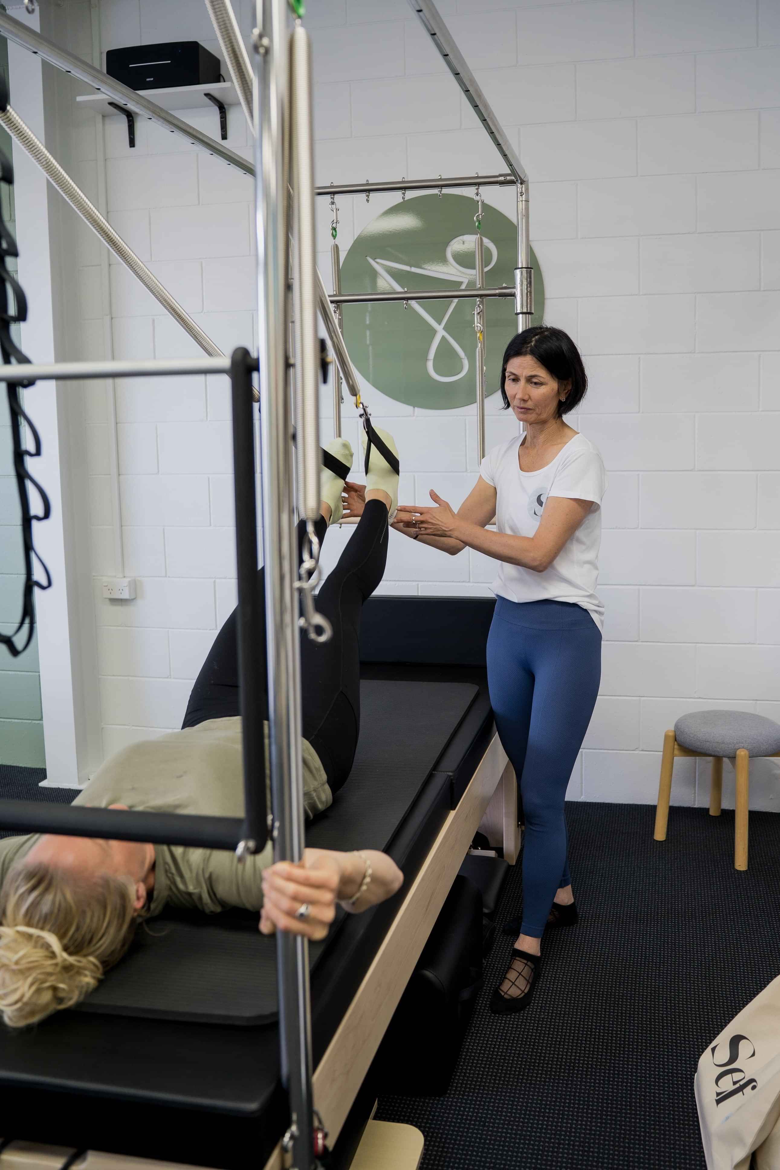 Image of instructor showing a woman how to do a Pilates exercise at Self, wellness studio in Alexandra.