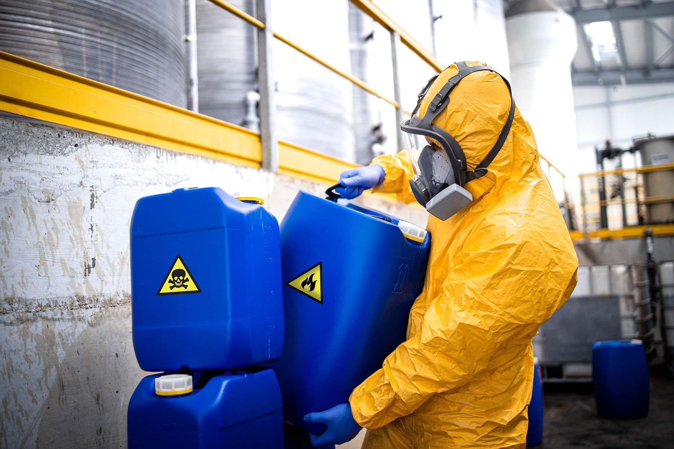A person in full protective gear moving chemicals