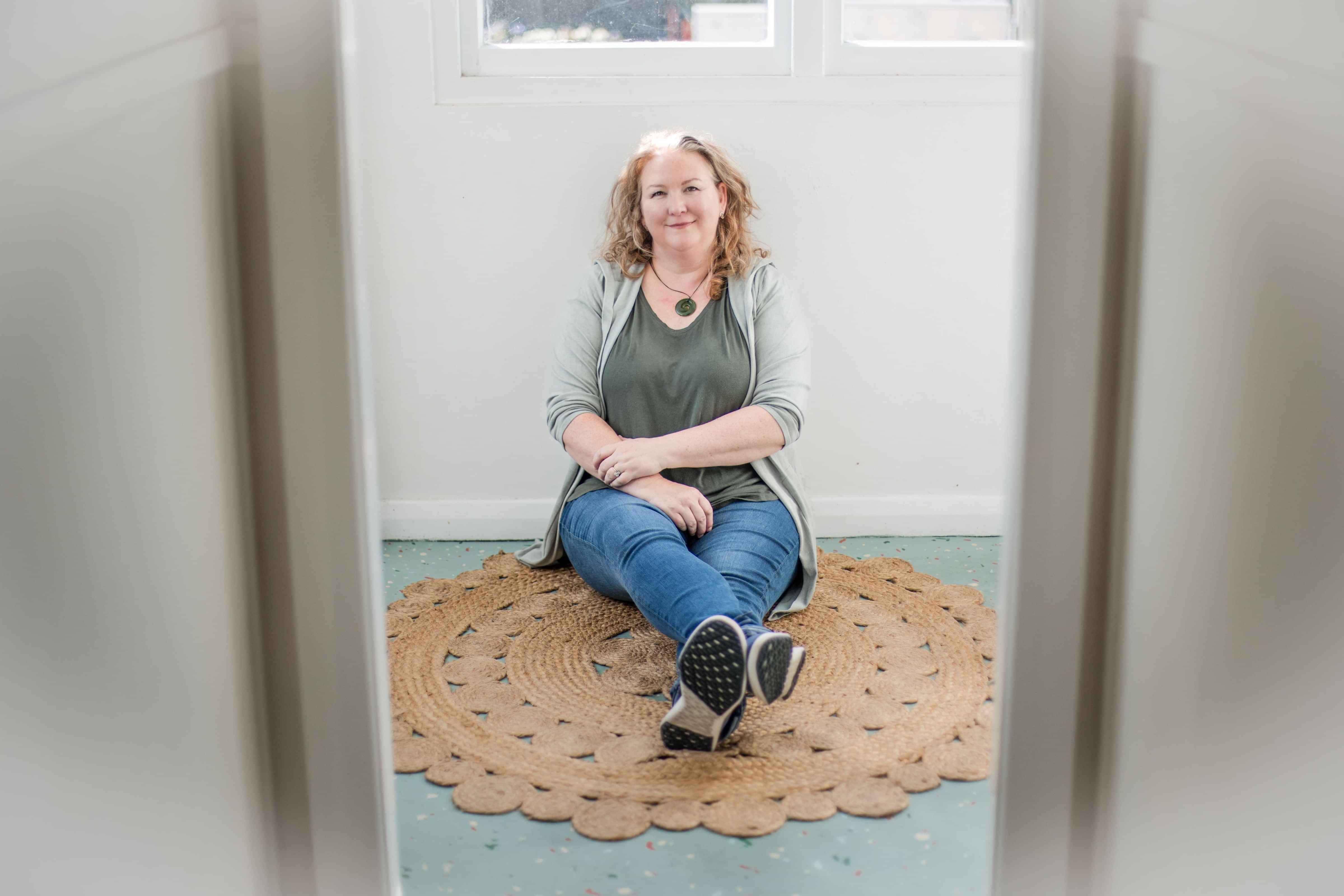 Photo of Elizabeth Marshall Mental Fitness & Mindset Coach sitting on the floor with legs stretched in front of her planning. Mindset Coaching.
