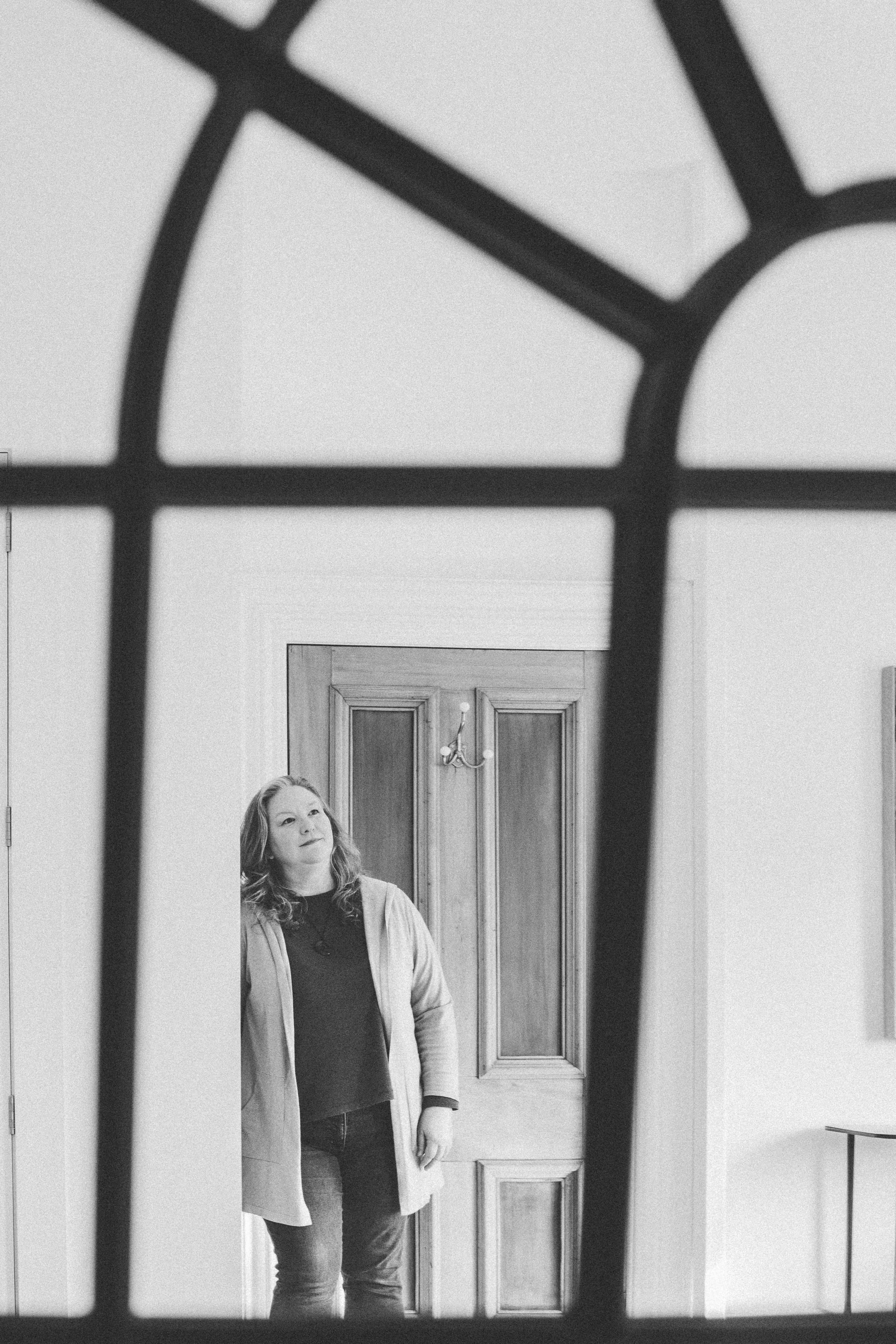 Black and white photos of Elizabeth, holistic health nutrition coach, leaning against a wall and looking away from the camera.