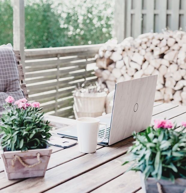 Laptop on outdoor desk with coffee and notebook – illustrating flexible, tech-driven AI and automation support for business owners.