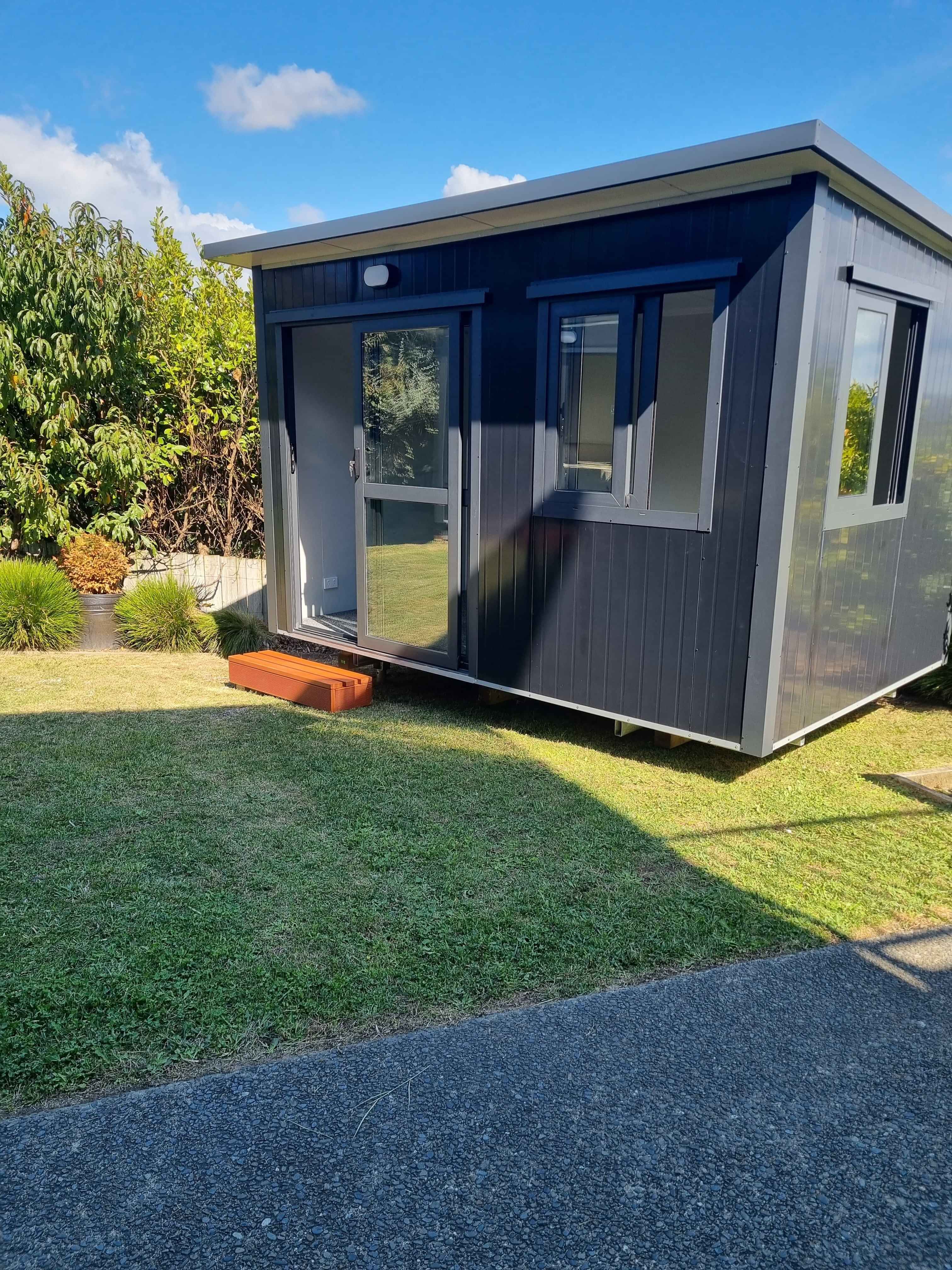 3.6m x 2.4m black cabin with two windows and entrance step