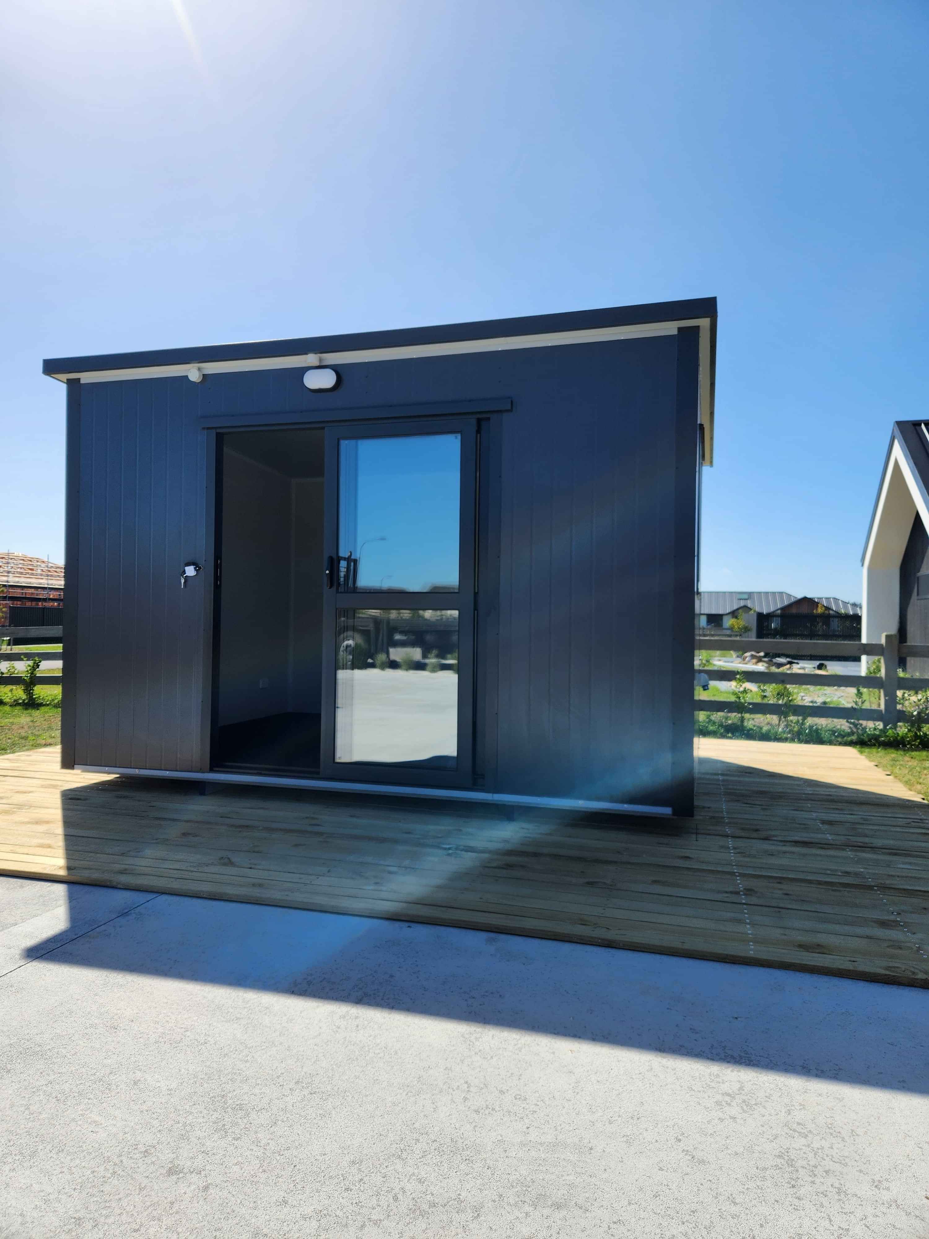 3.6m x 2.4m black cabin with two windows and entrance step