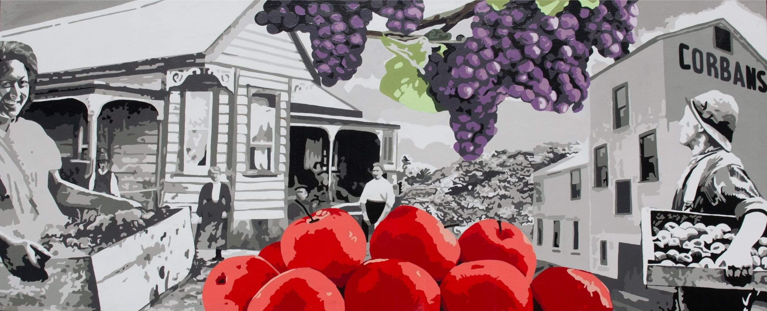 Painted mural with bright red apples and purple grapes in the foreground with a cottage and industrial building in the background