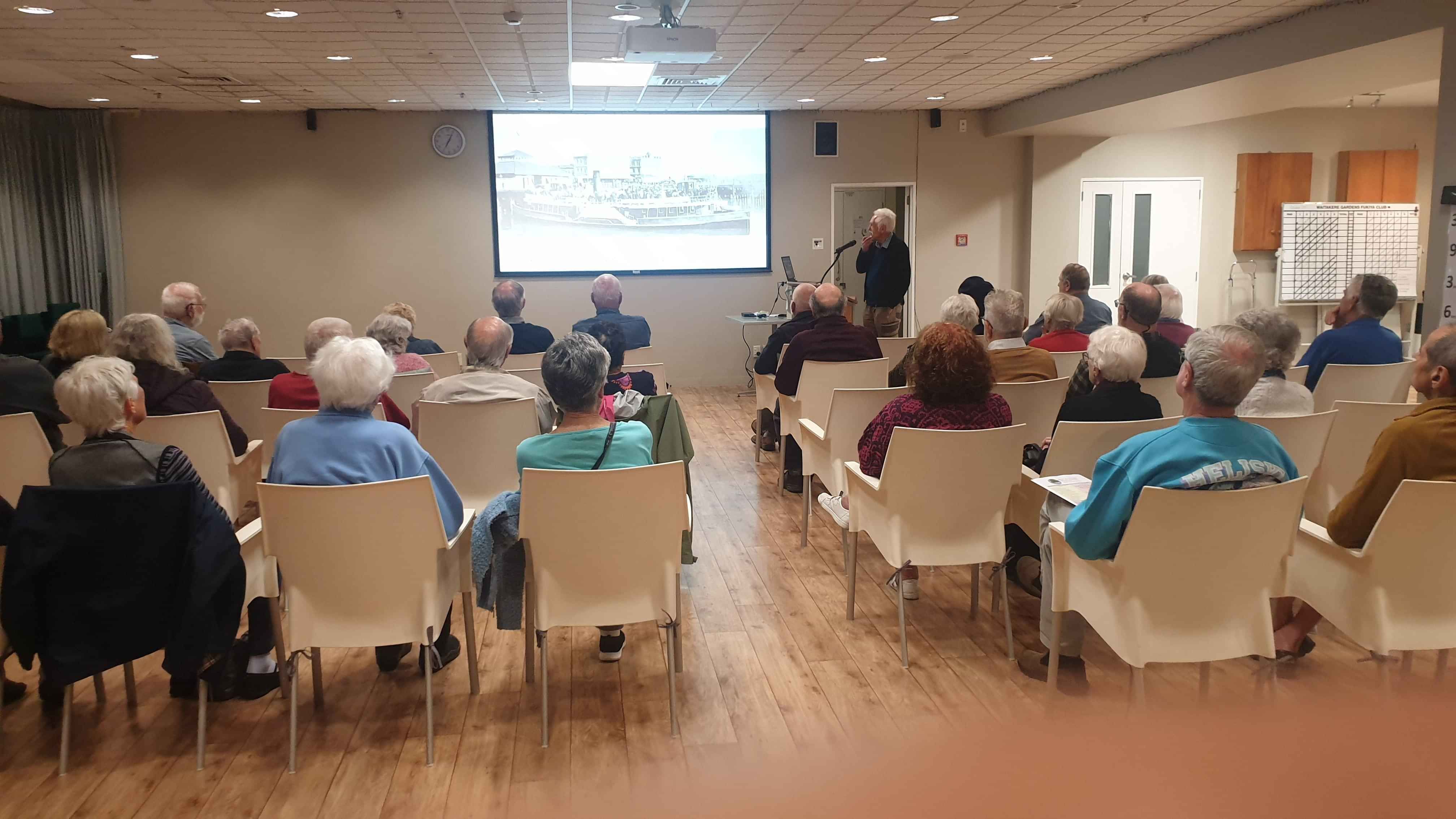 People seating in rows watching and listening to a presentation