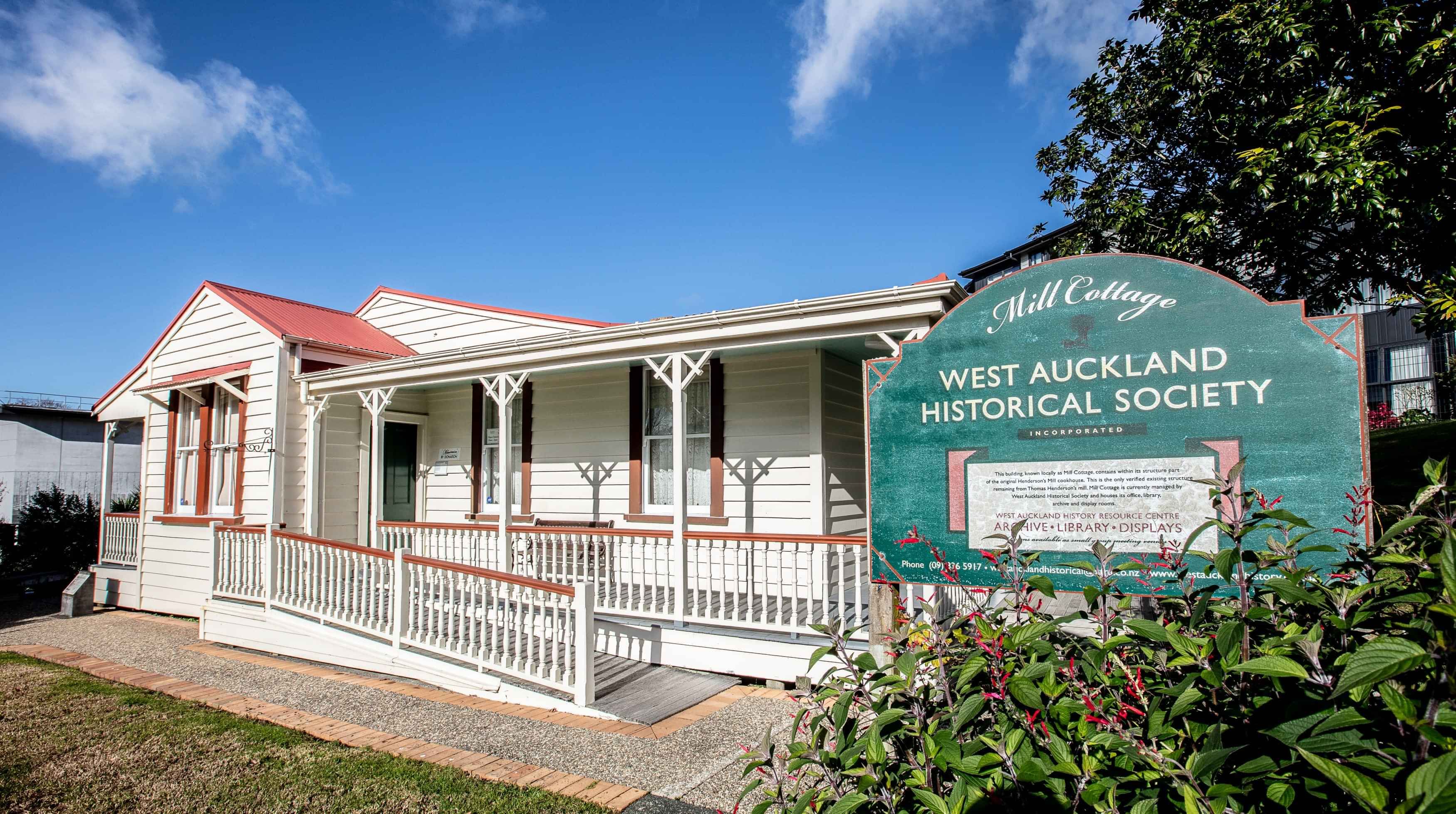 A single story white wooden building with an orange roof