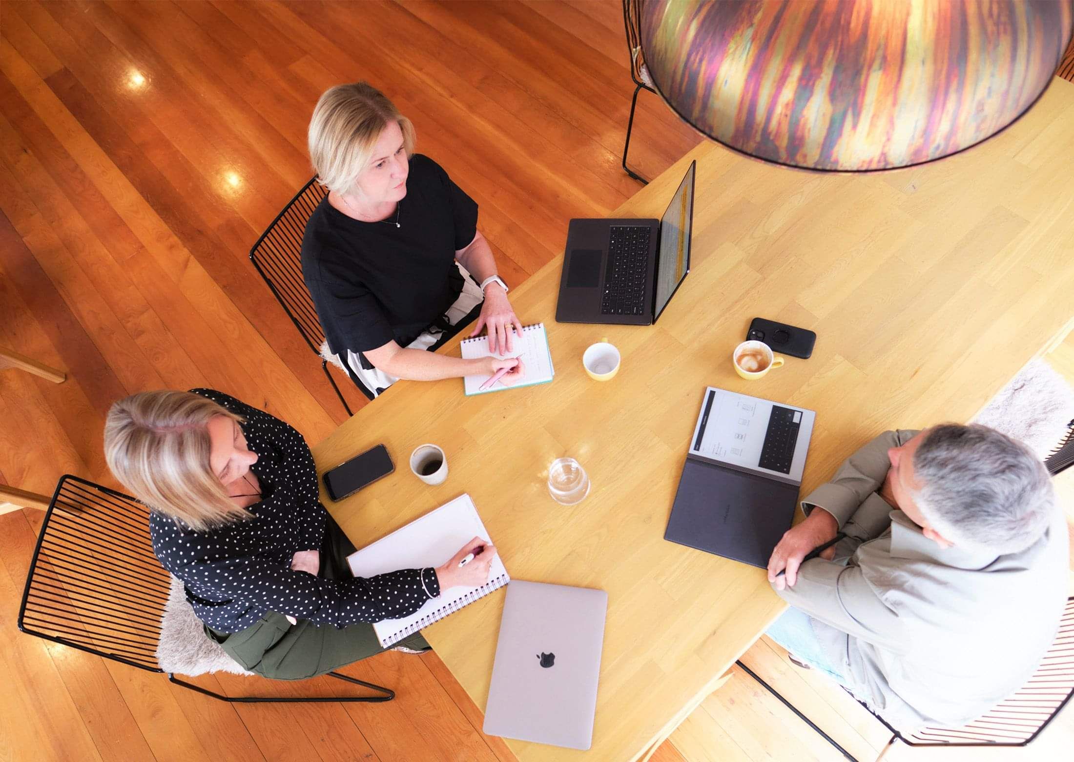 Photo of Gabrielle Ralph and Claire Turner from Two Little Birds Consulting sitting around a table consulting with a client