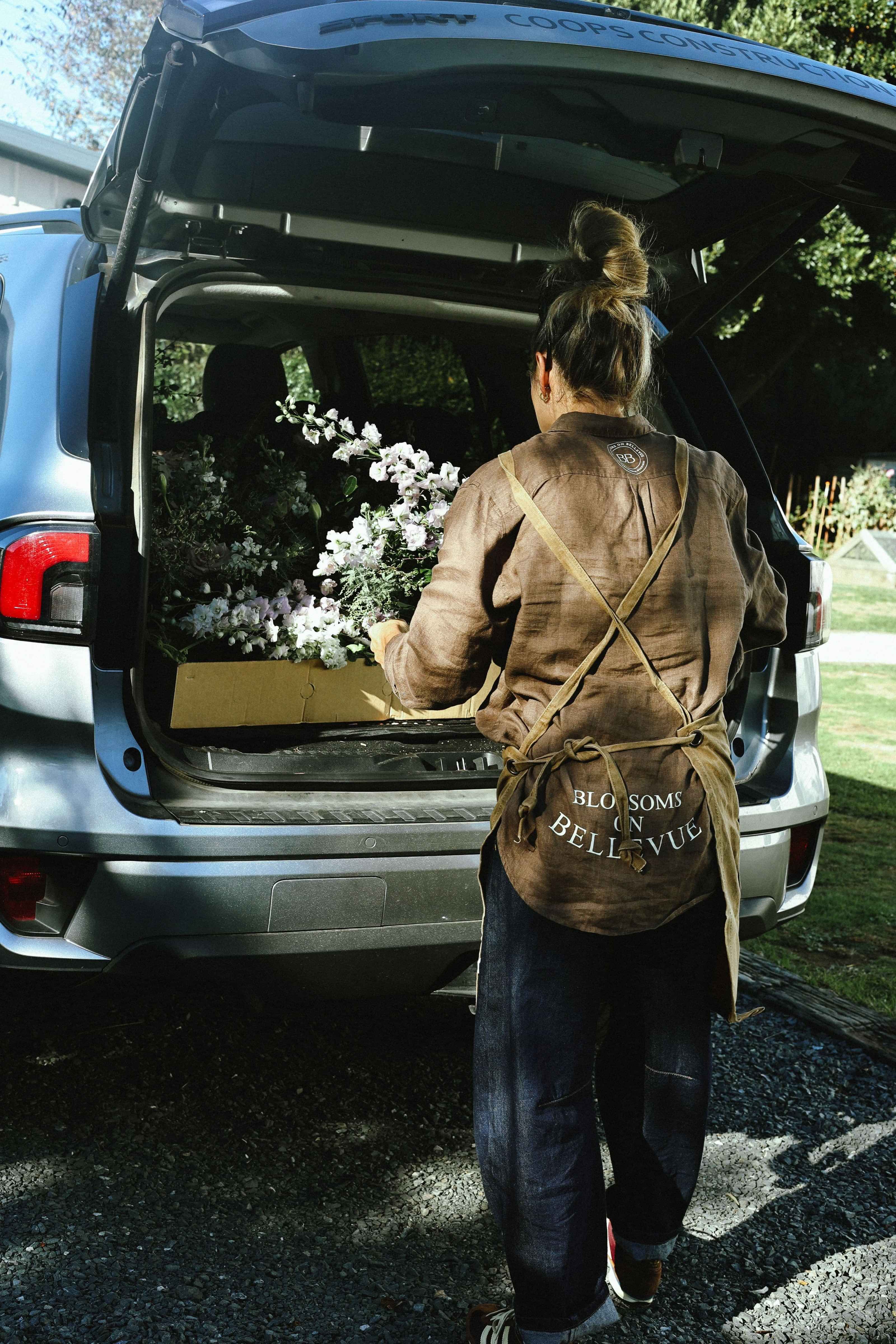 Back of Florist apron and brown shirt with 'Blossoms on Bellevue' text, worn by a local florist in Cambridge, New Zealand