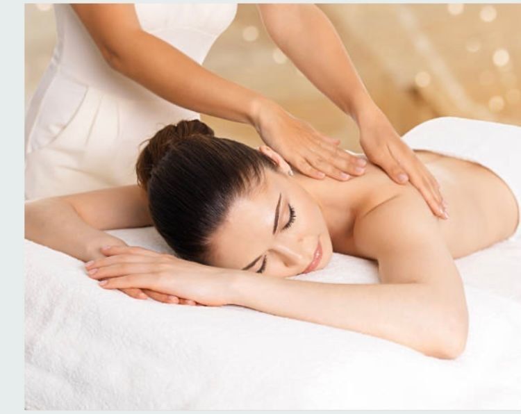 Lady with black hair lying on the massage table with her head facing to the side having a back massage