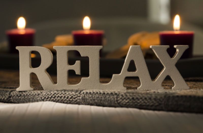 Picture of a large Relax sign with red candles lit in the background