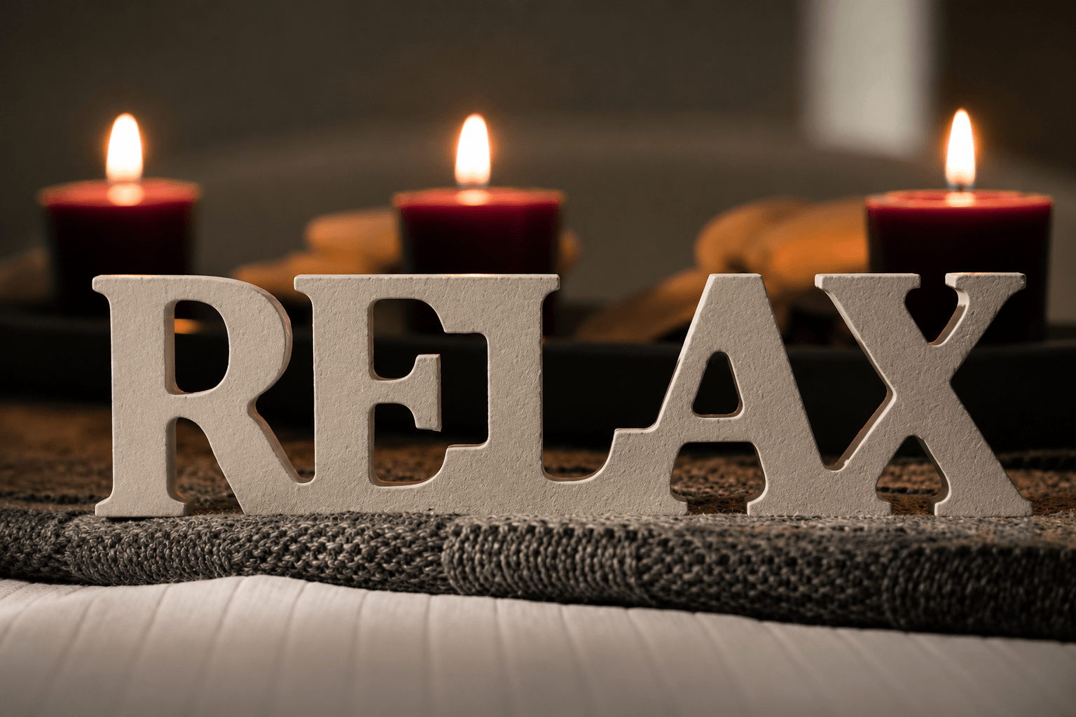 Picture of a large Relax sign with red candles lit in the background