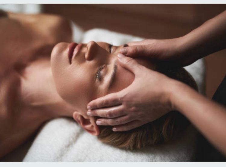 Massage therapist performing a calming head massage for a client lying down – relaxation massage Cambridge
