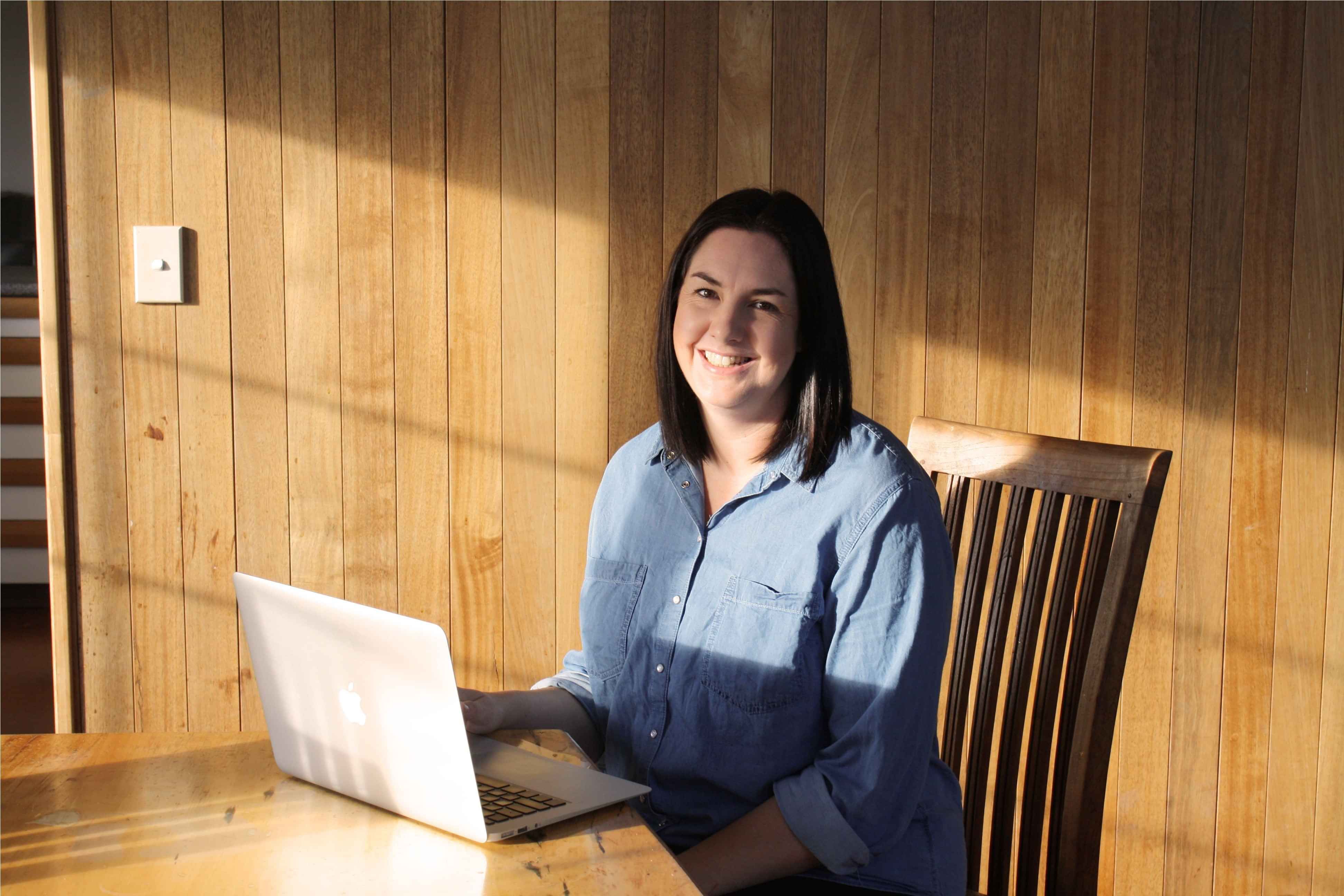 Female sitting at a laptop smiling at camera