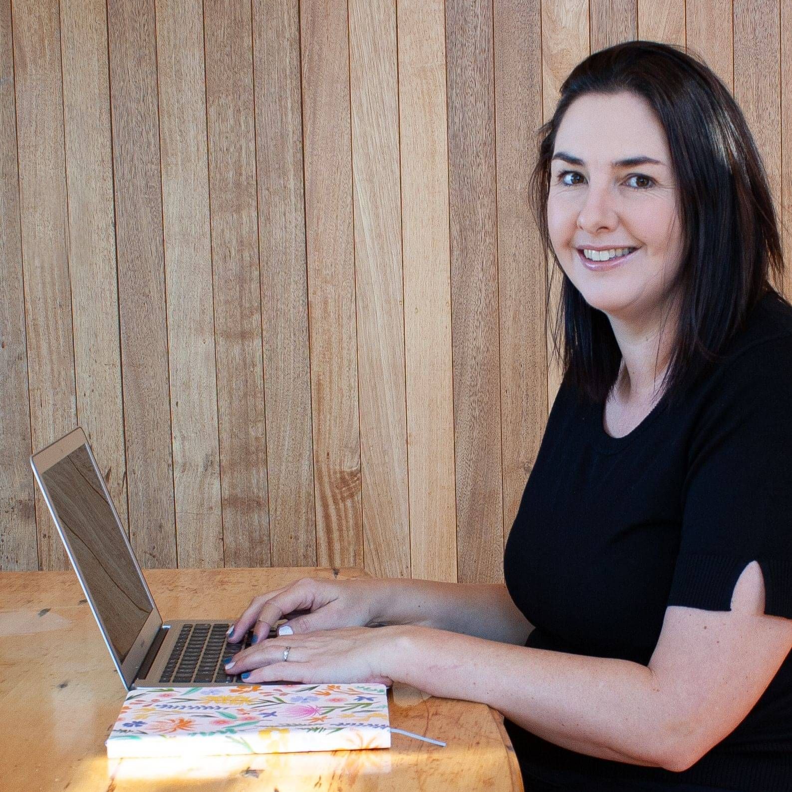 Female sitting at a laptop smiling at camera