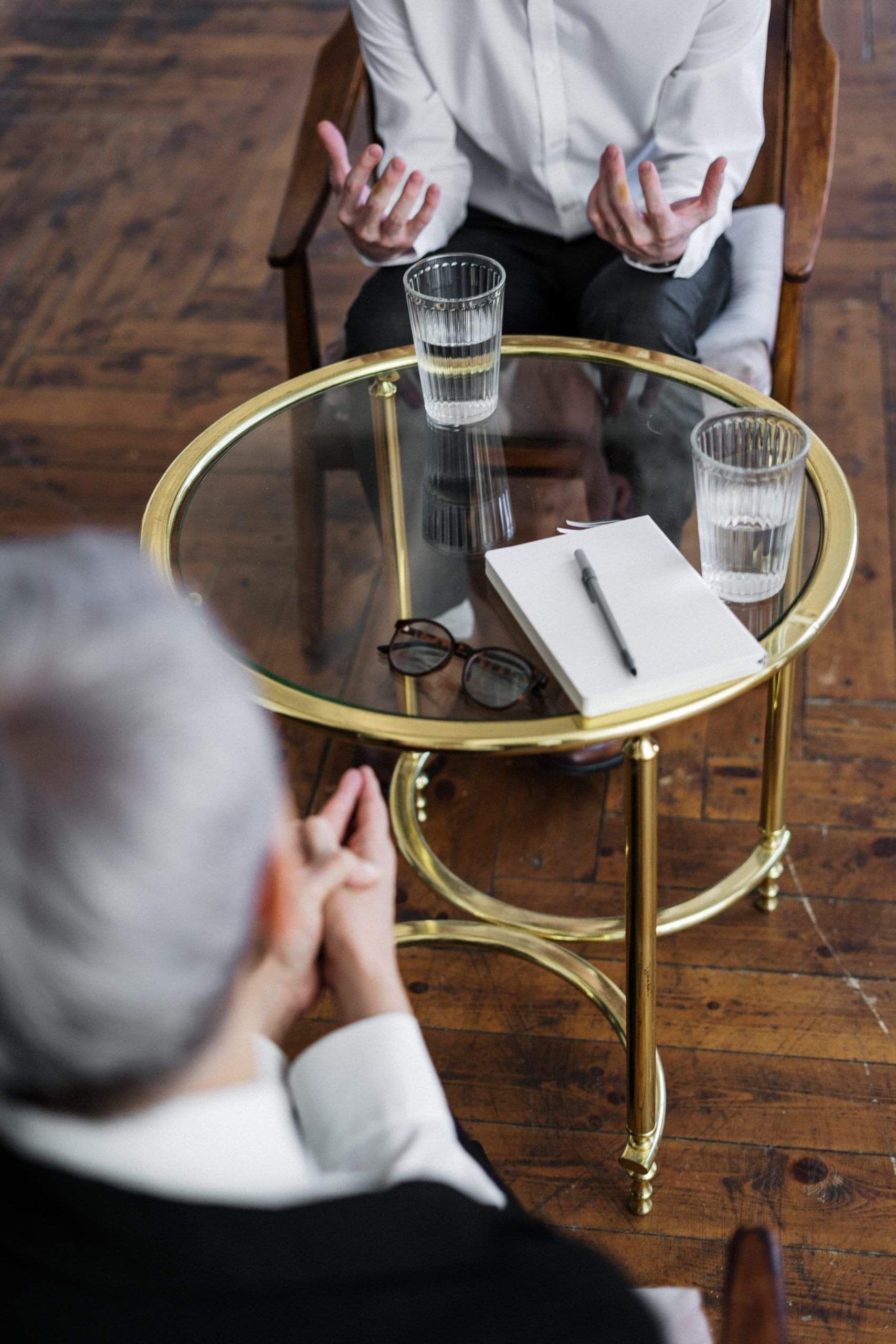 People talking together, sitting across from one another at a table.
