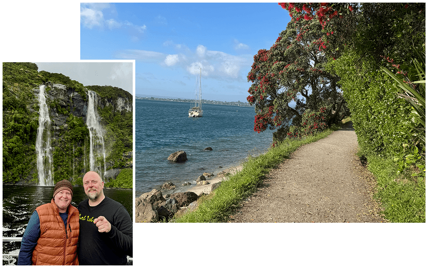 Two people with a waterfall at Milford Sound in the background alongside a scenic coastal walking track in New Zealand.