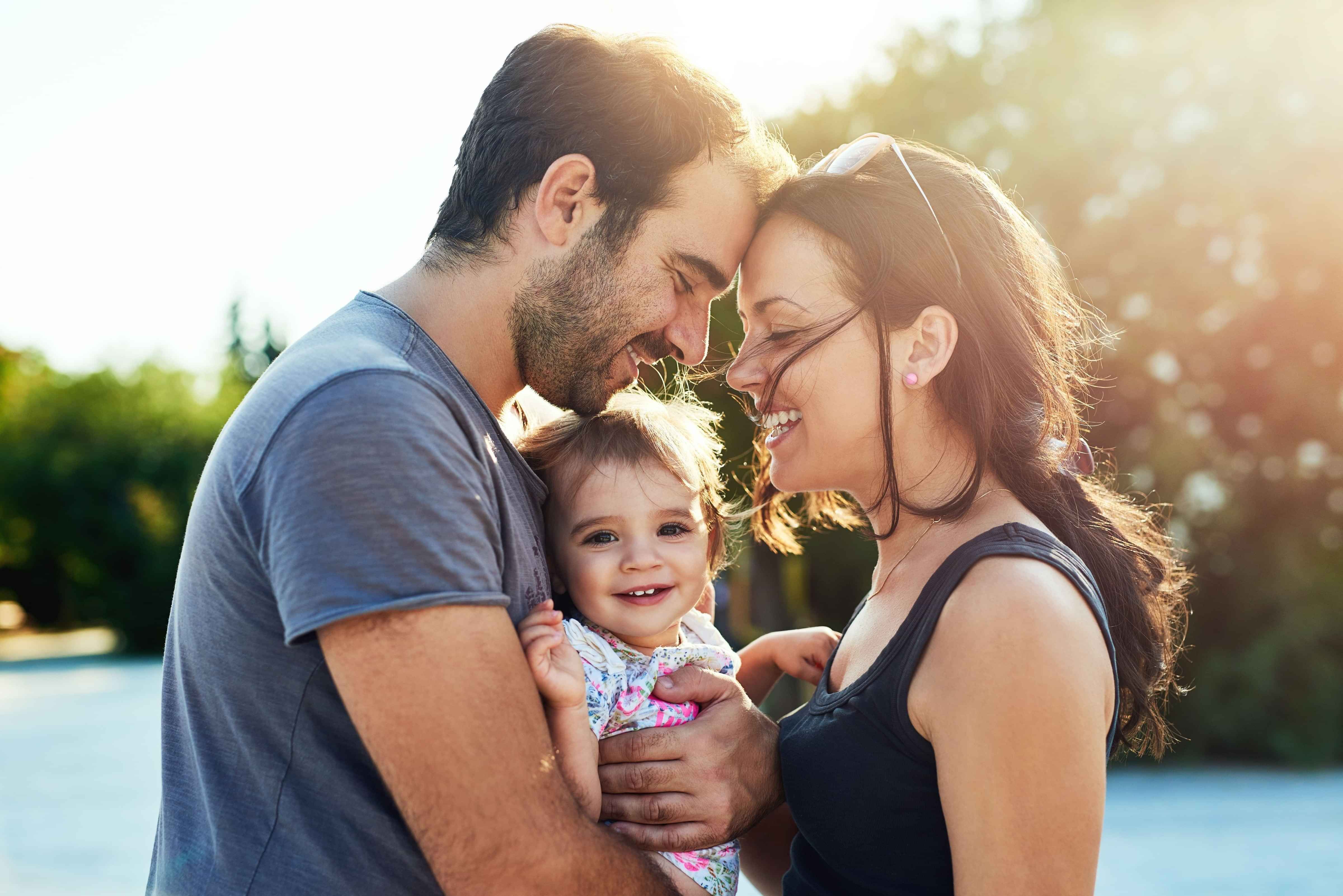 Young dad, baby daughter and mum hugging