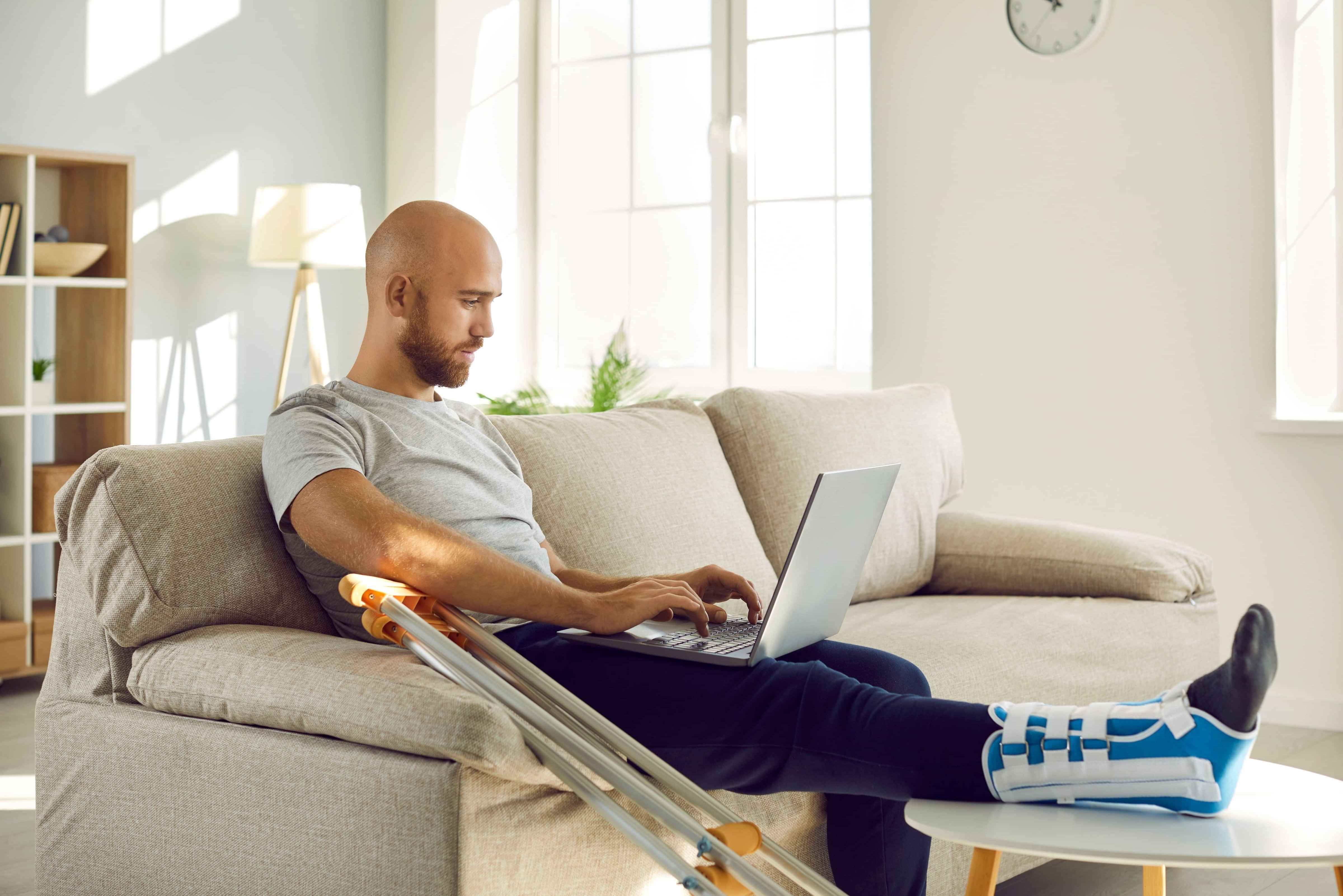 Young man sitting on couch with broken leg