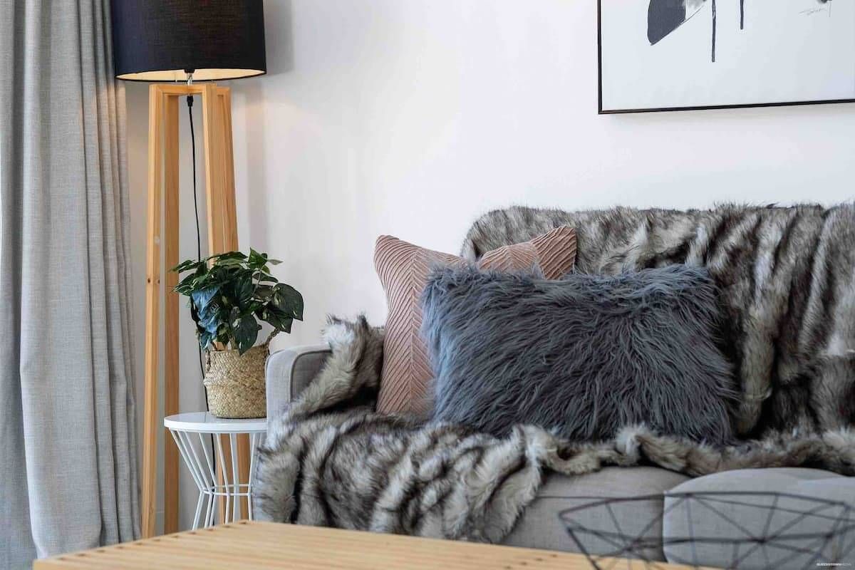 A cozy couch at a Cambric holiday property set up with throw cushions.