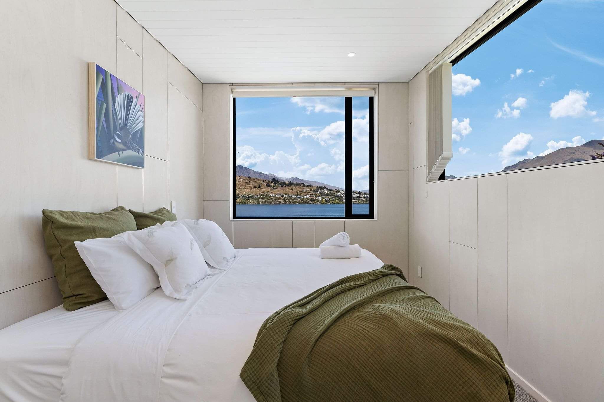 A bed with white and green linen at one of Cambric's AirBnB properties.