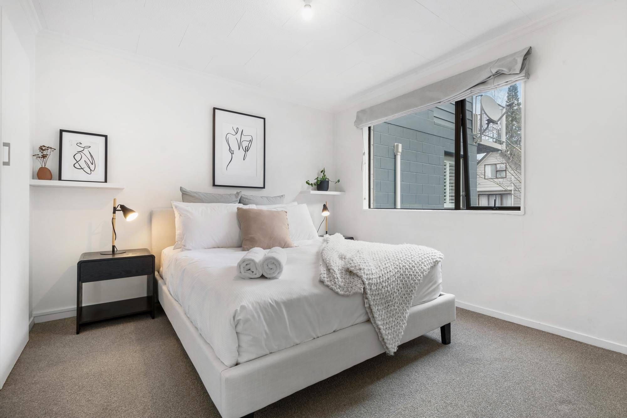 A light and bright master bedroom staged with white linen and wall art work at one of Cambric's AirBnb properties.