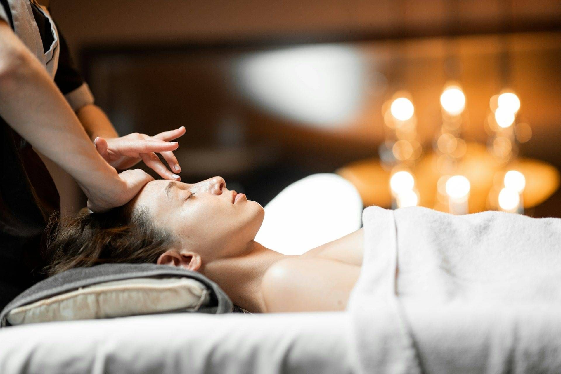 A client lying on a treatment bed, receiving a beautiful facial massage during a skin treatment.