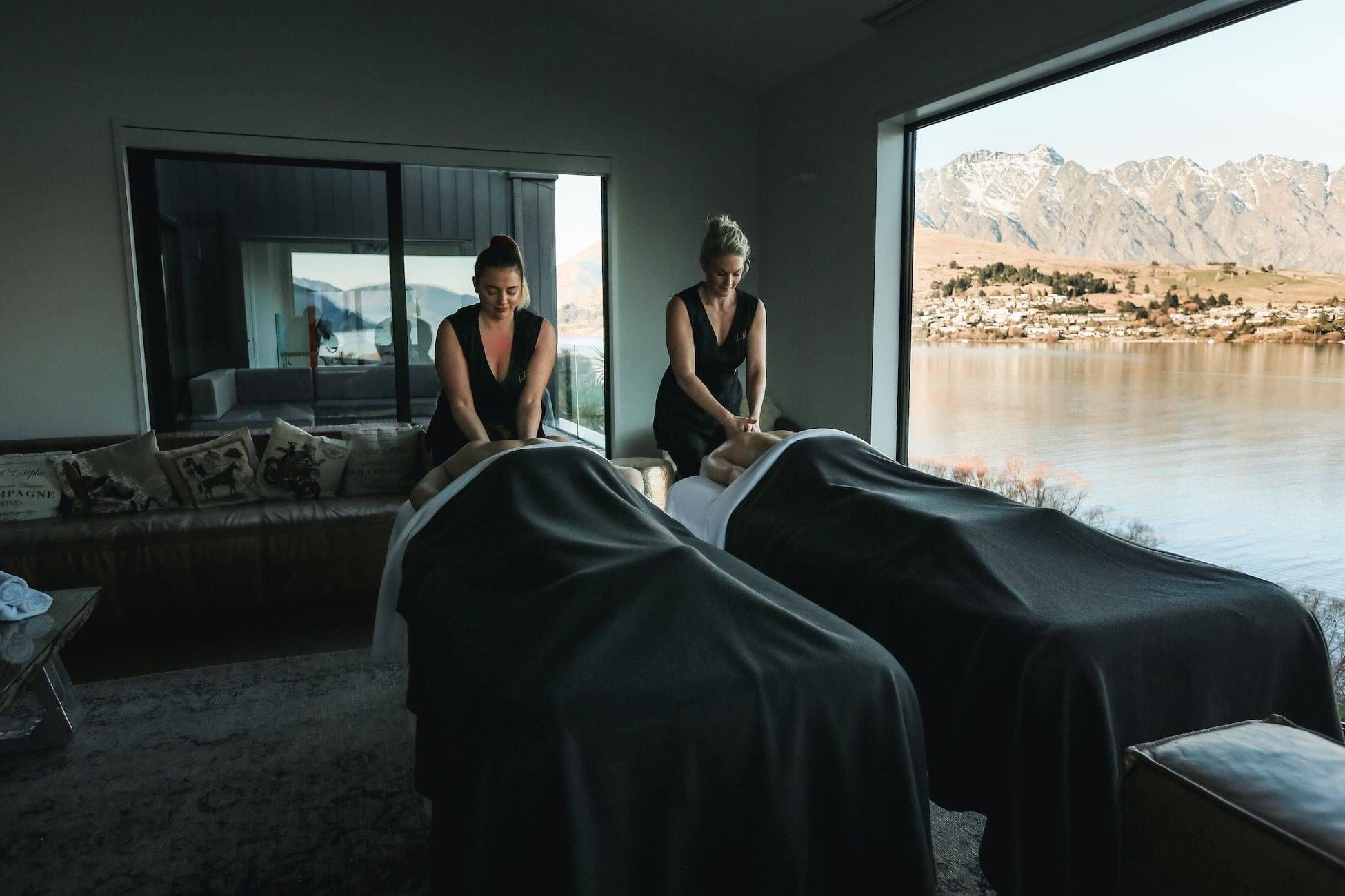 A couple getting massages at their accommodation with a beautiful Queenstown lake view in the background.