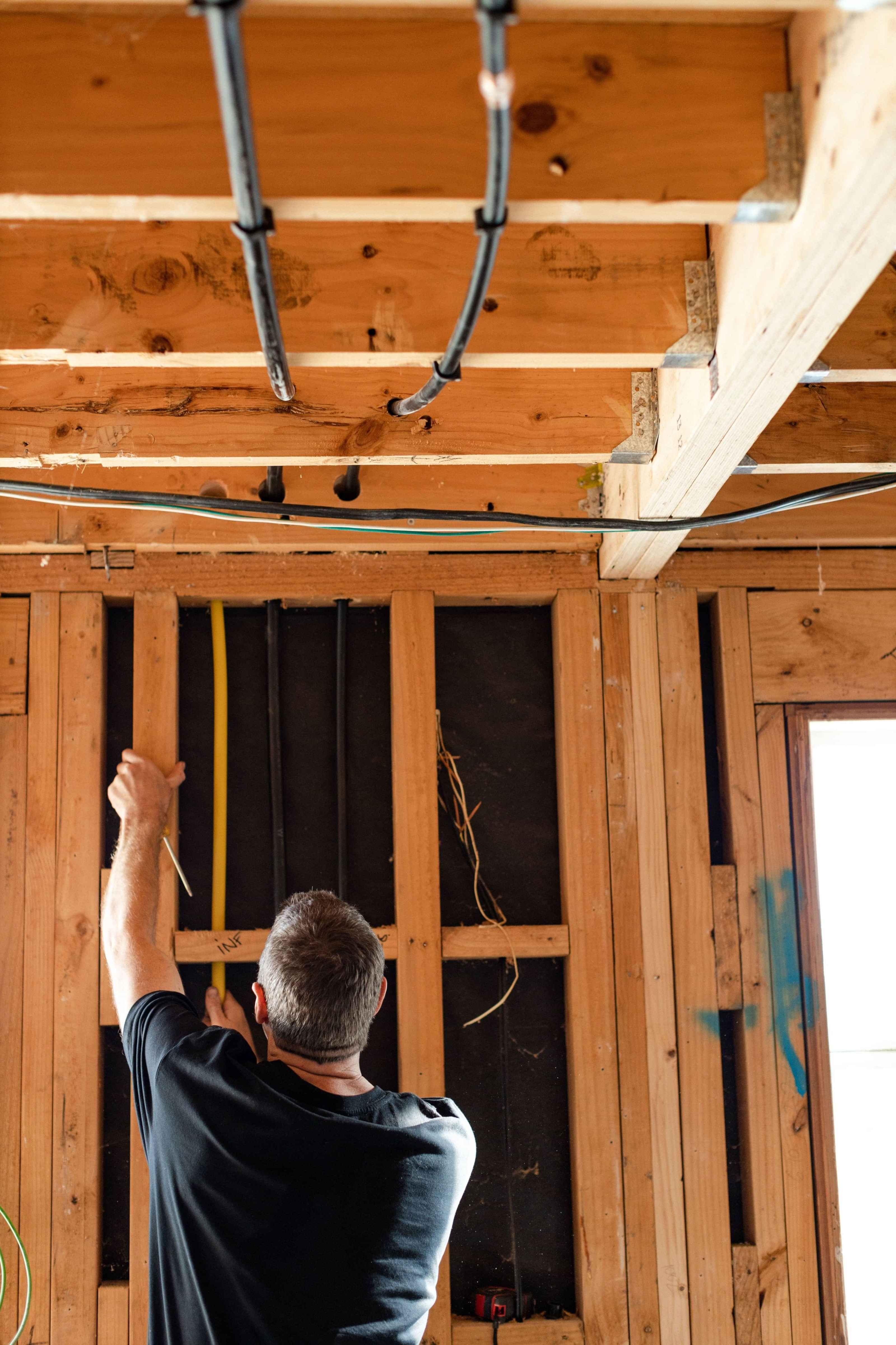 A plumber fitting pipes in a framed wall. 