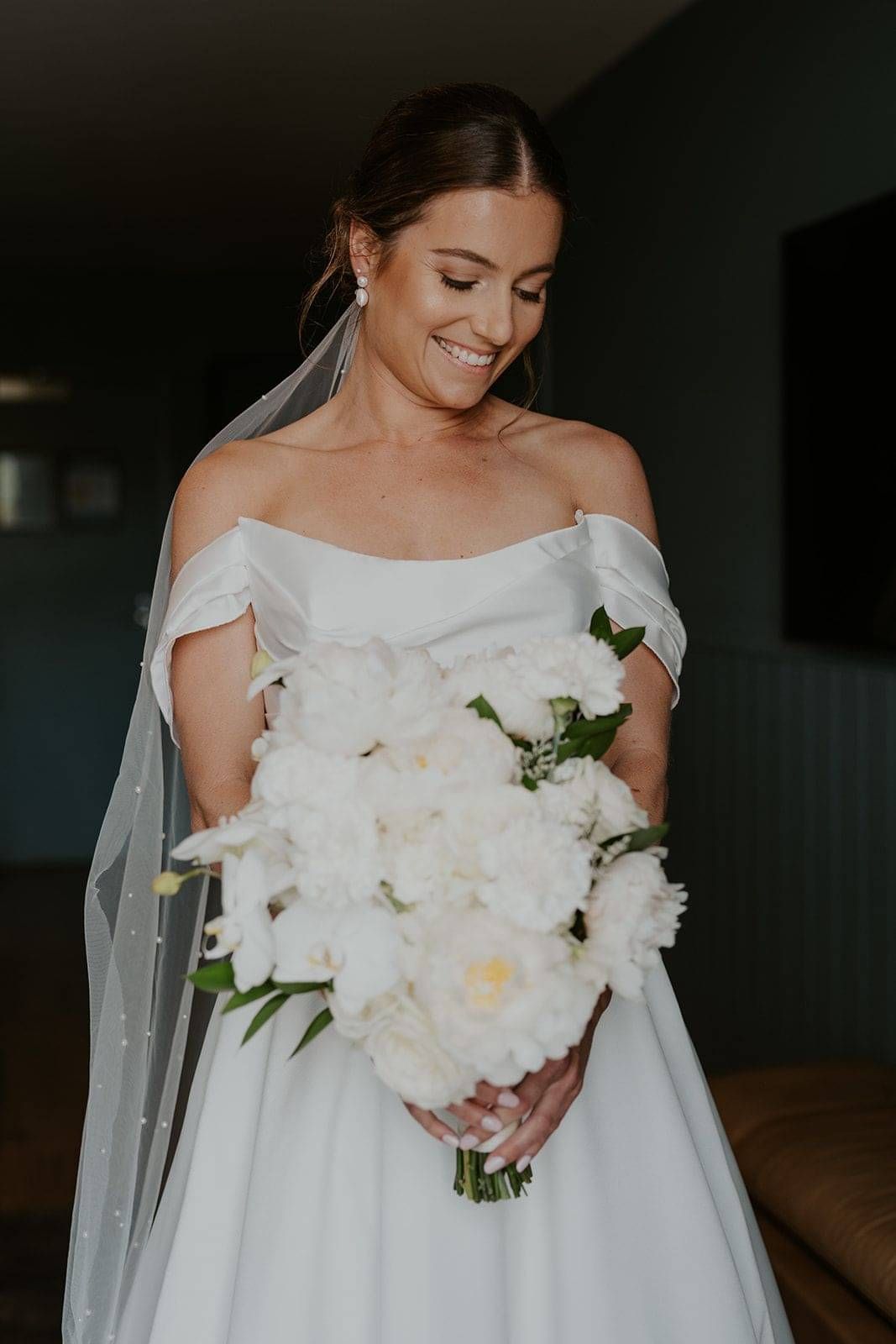 A bride holding a white bouquet with hair styled by Georgie.
