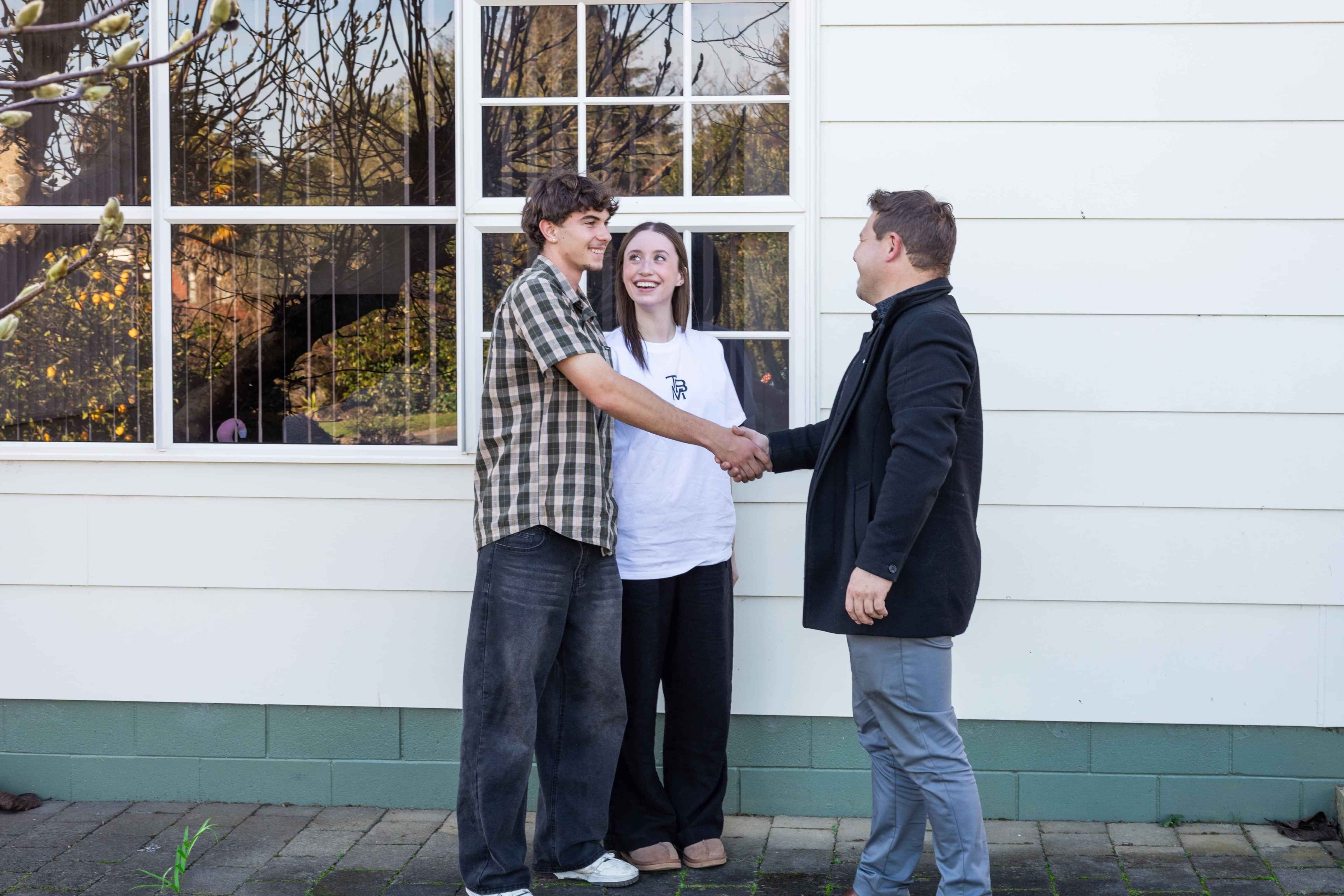 Insurance Adviser shaking hands with a young couple purchasing their first home
