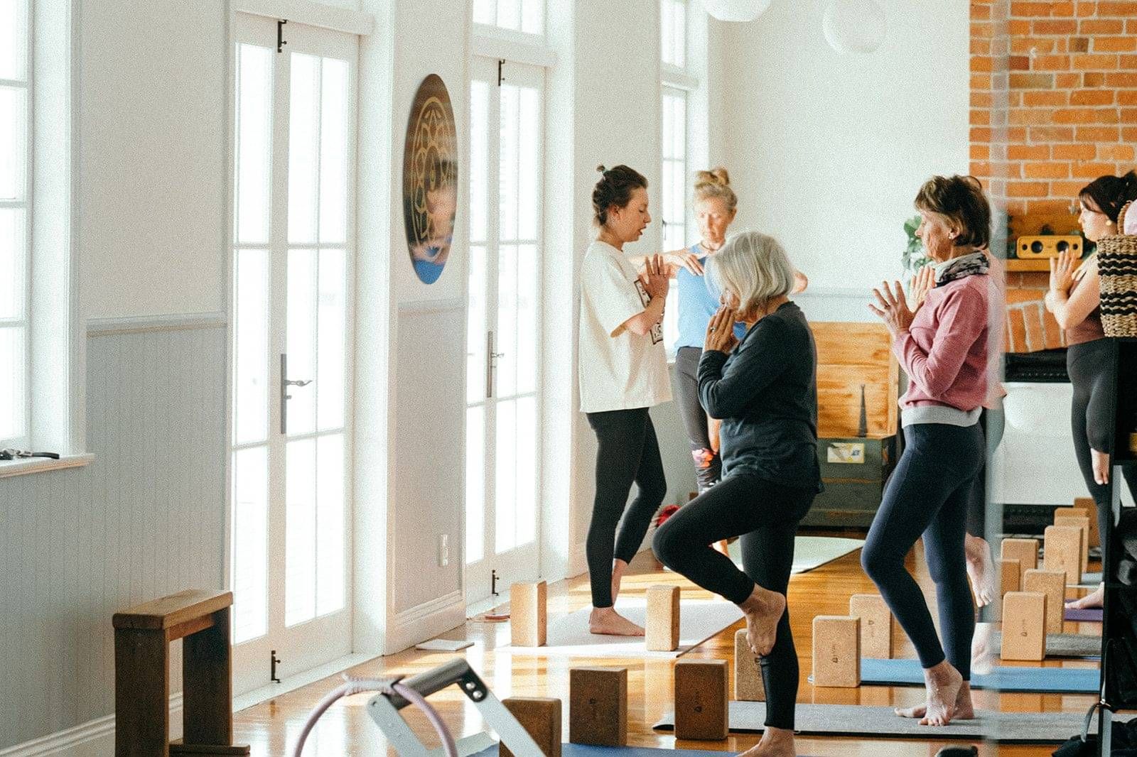 A yoga teacher instructing her class in a Tree Pose (Vrikshasana)
