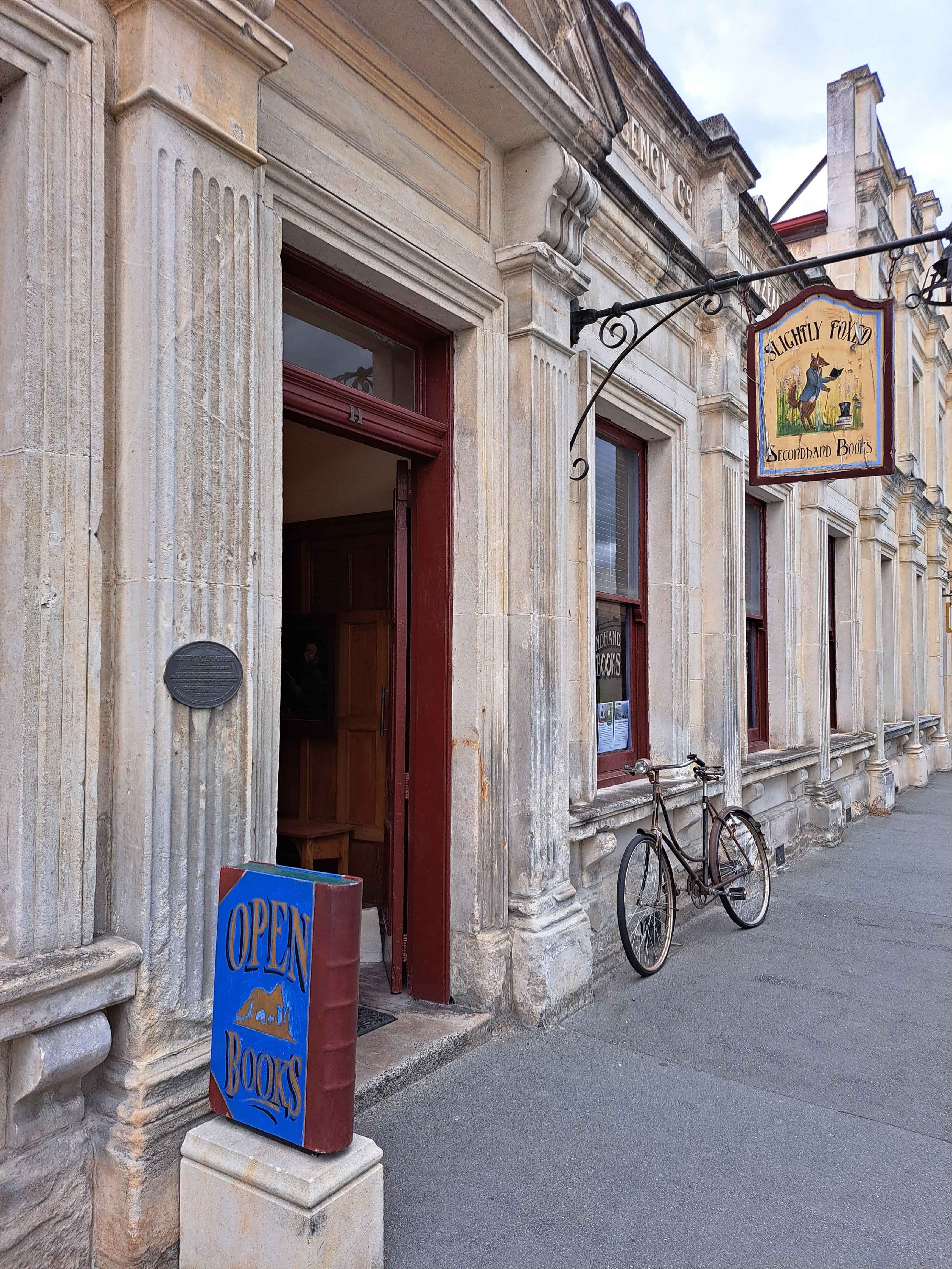Outside of an early 1900s building housing a book shop, with a bicycle outside