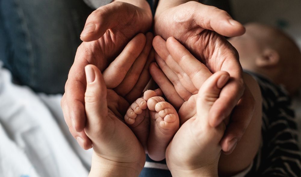 Baby’s feet held by adult hands, reflecting adoption and surrogacy legal advice in NZ