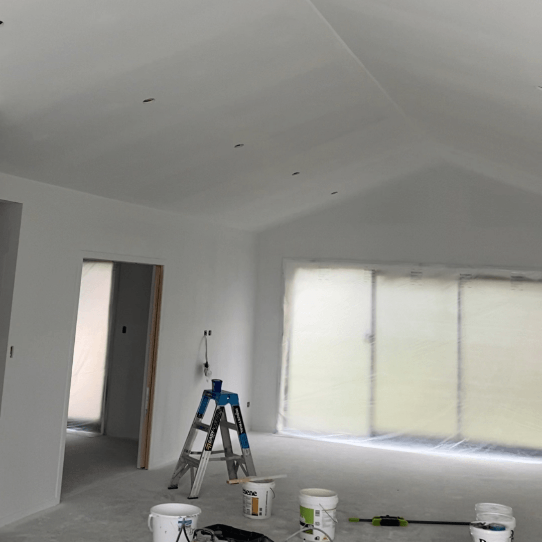 Prep work for painting interior of home.  Ladders paint cans and plastered and primed walls.