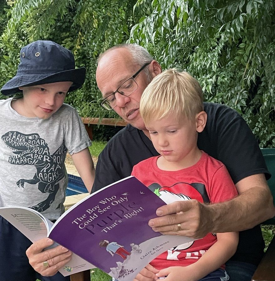 Dad reading the Boy Who Could Only See Purple book to his two young sons