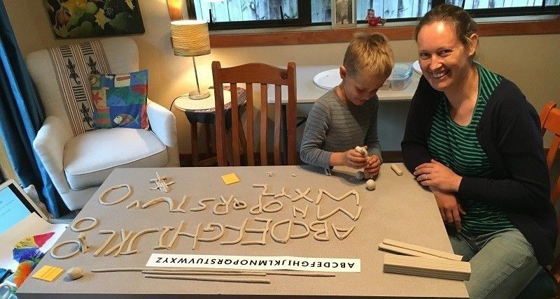 Child sitting at table with mum and claying the alphabet