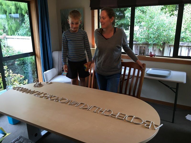 Kid standing on chair at table with the clay alphabet in a line