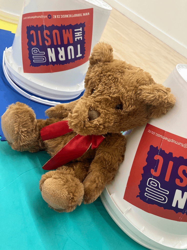 A teddy bear sat with 'Turn Up the Music' buckets.