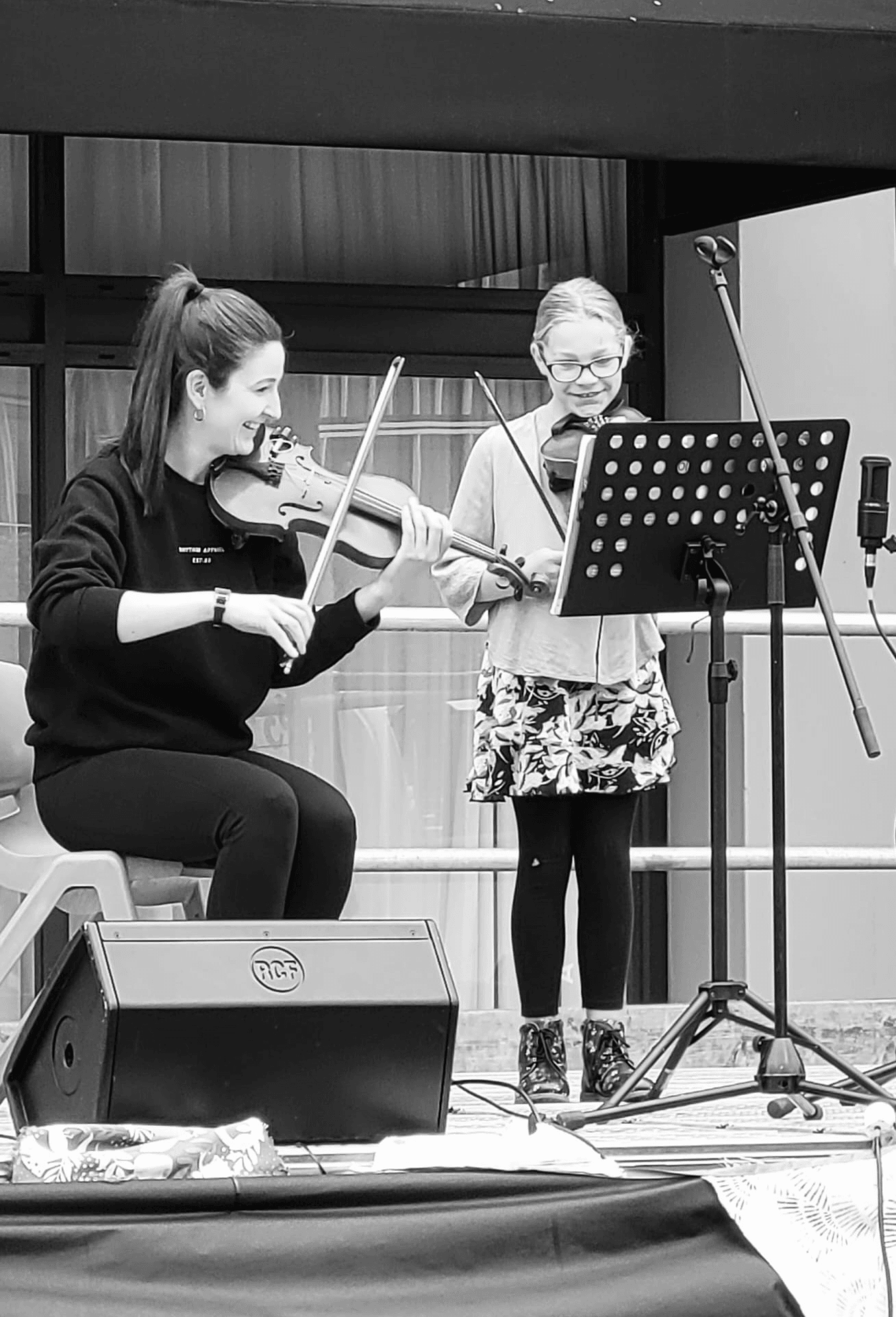 Erica playing violin alongside one of her students.