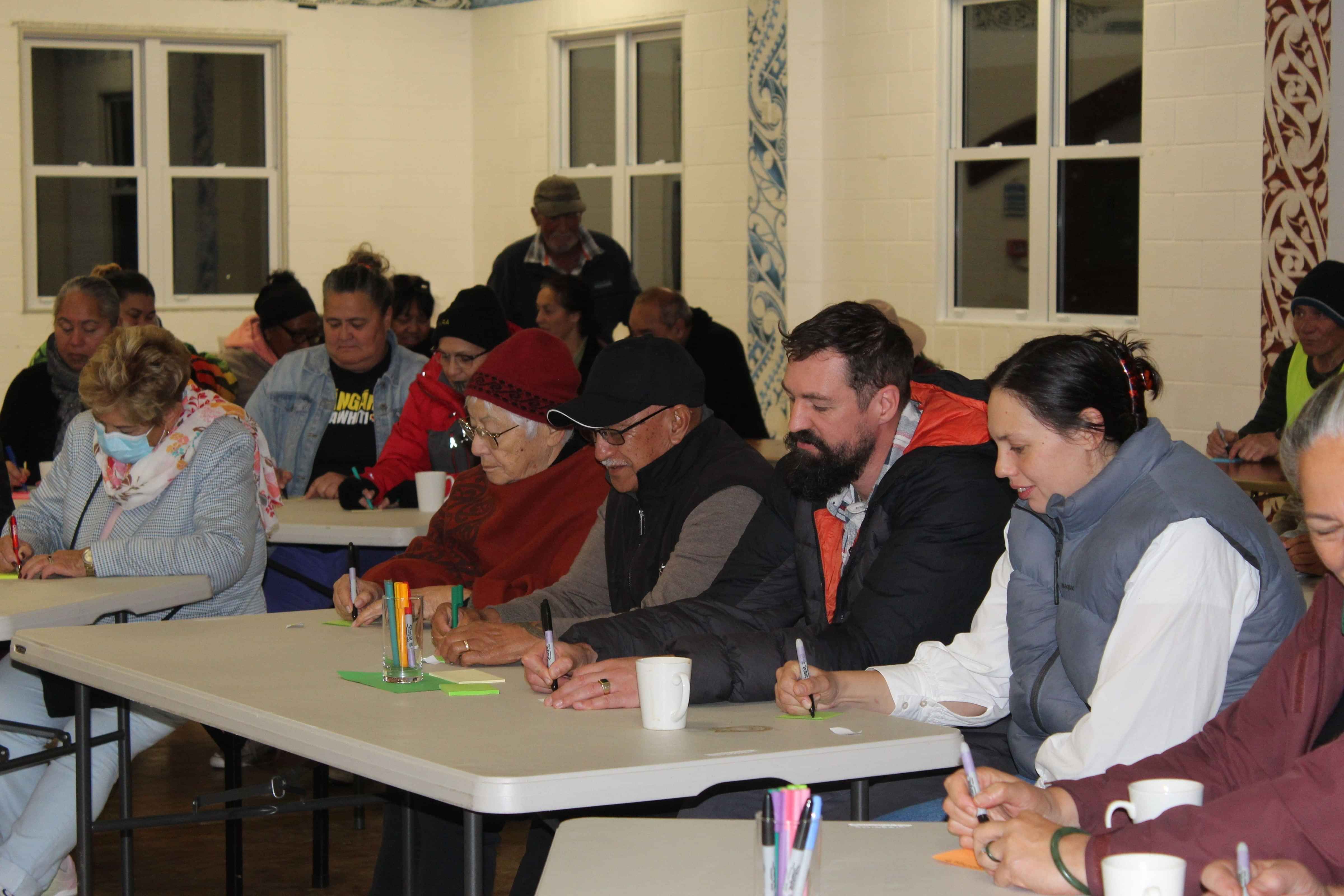 Community members participating in a facilitated strategy session with AraHina, taking notes and sharing insights.