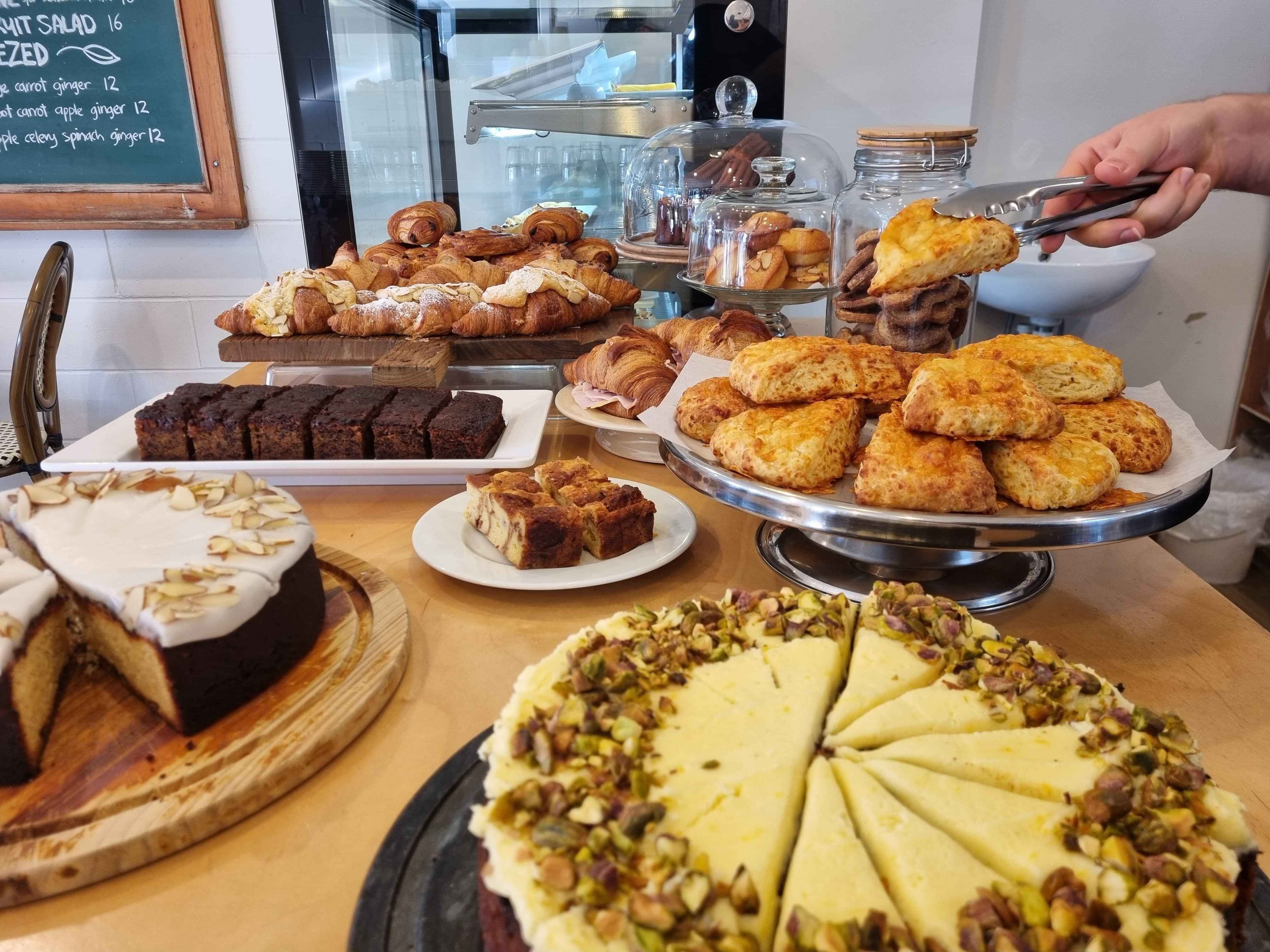 counter full of food, scone being grabbed by server