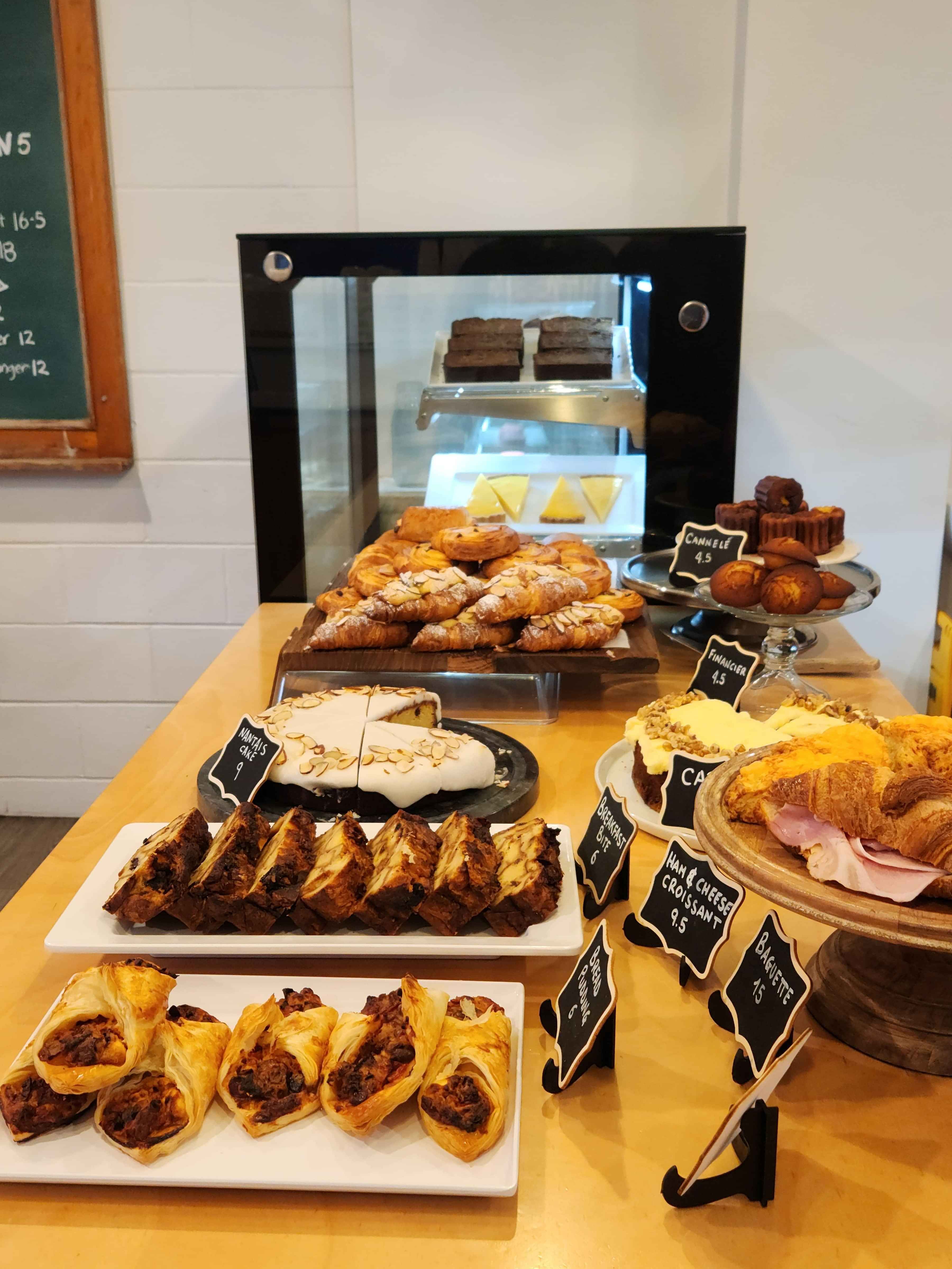 counter full of food, scone being grabbed by server