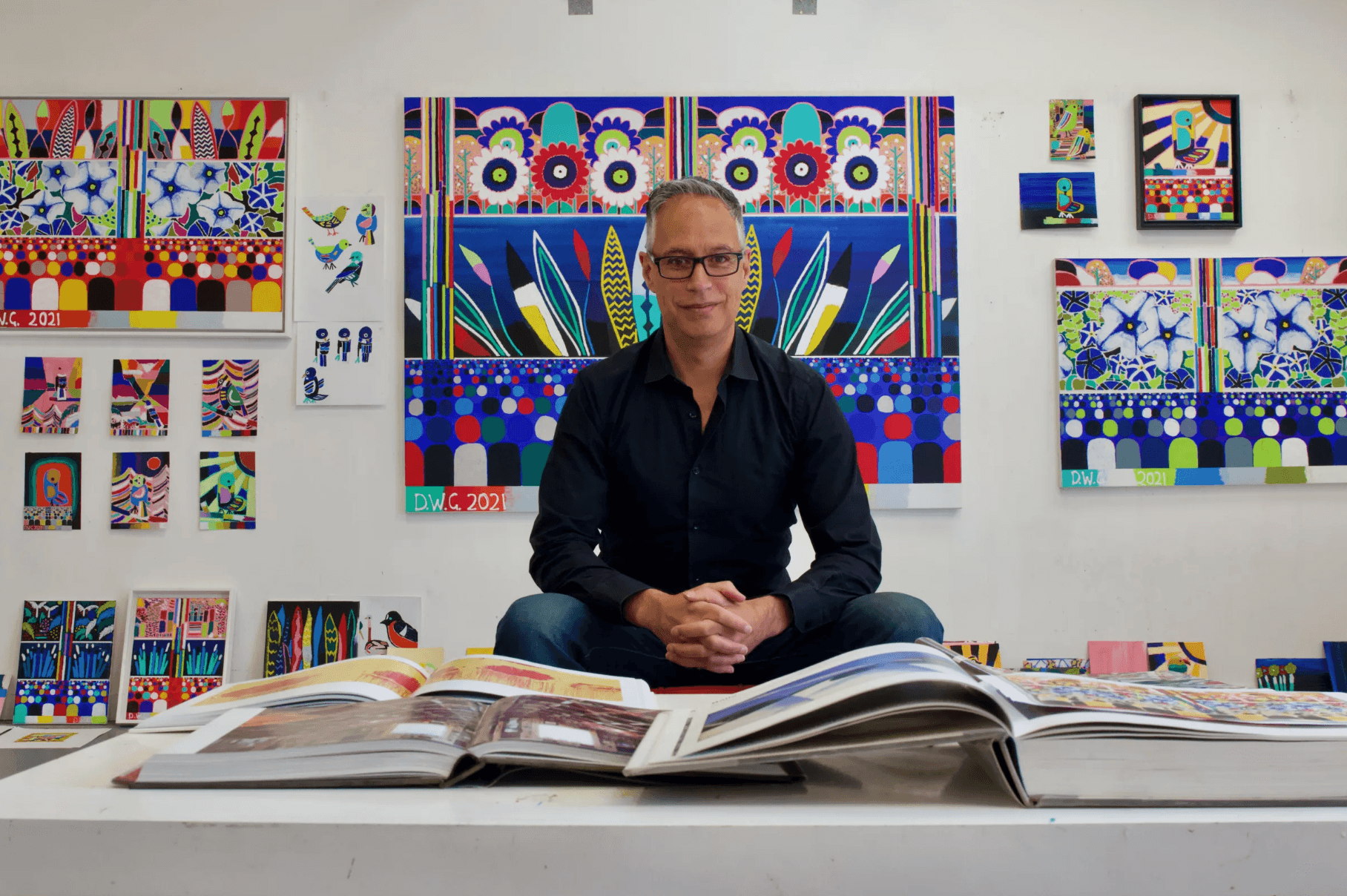 Photo of Darryn George with his paintings behind