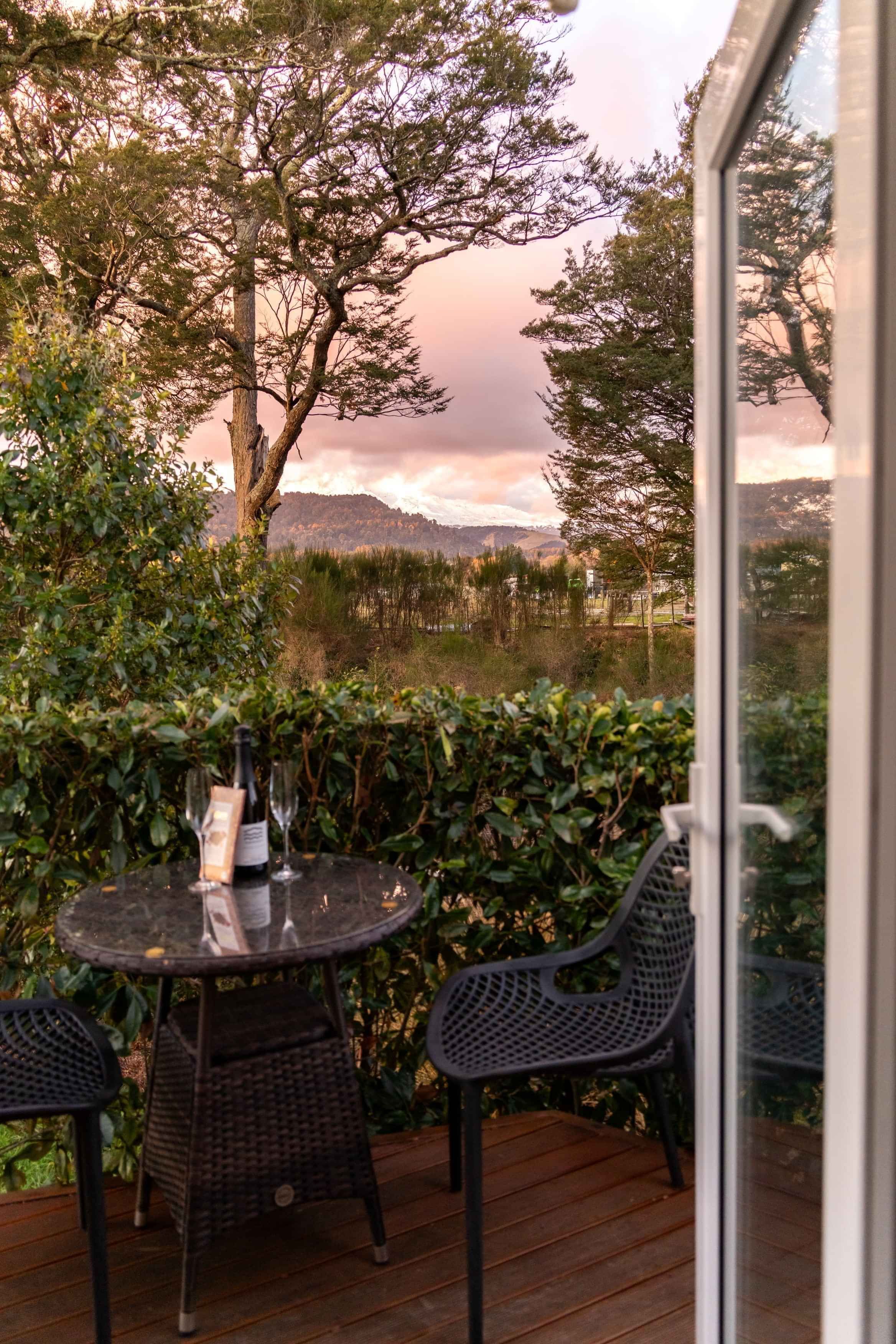 Wine and chocolates on the Mangawhero deck, with Mt Ruapehu rising beyond a landscape glowing pink at sunset.