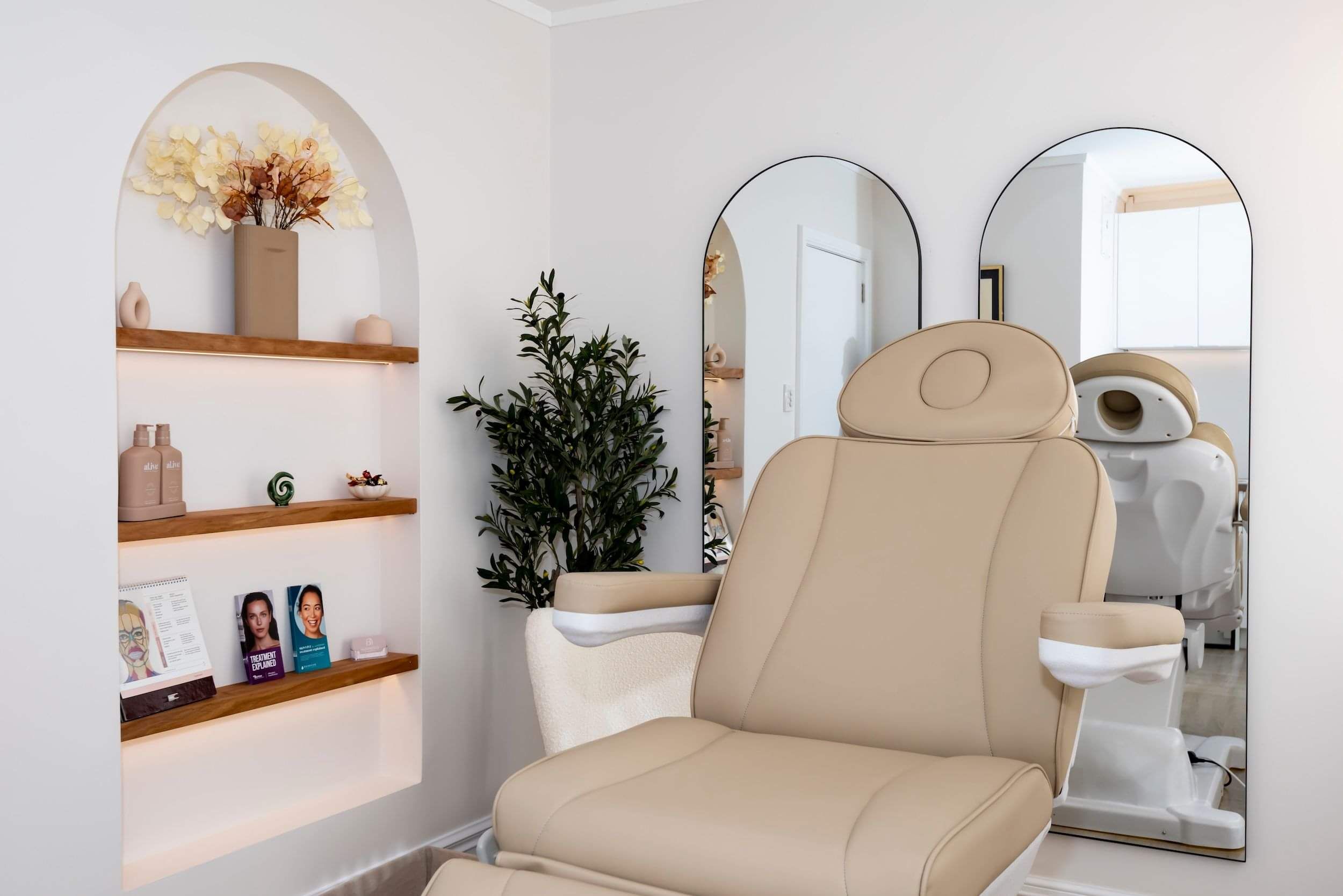 Bronwen's Remuera clinic interior with comfortable treatment chair, and an arched shelf featuring decor and products.